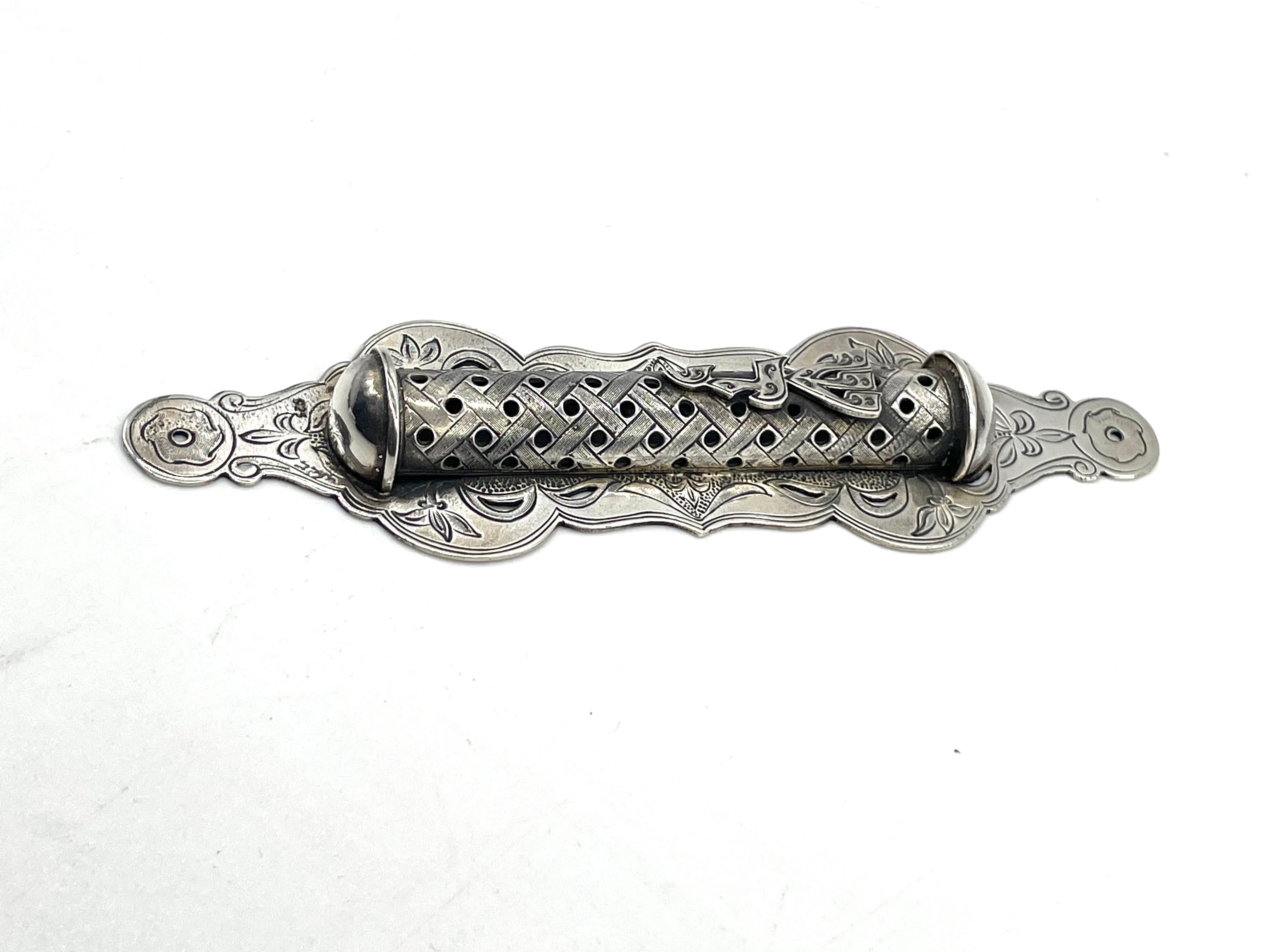 Late 20th century silver Mezuzah case handmade by the artist Shuki Freiman. The base of the mezuzah case is adorned with floral engraving throughout, while the cylinder is decorated with geometrical pattern and hollowed circles to reveal the scroll