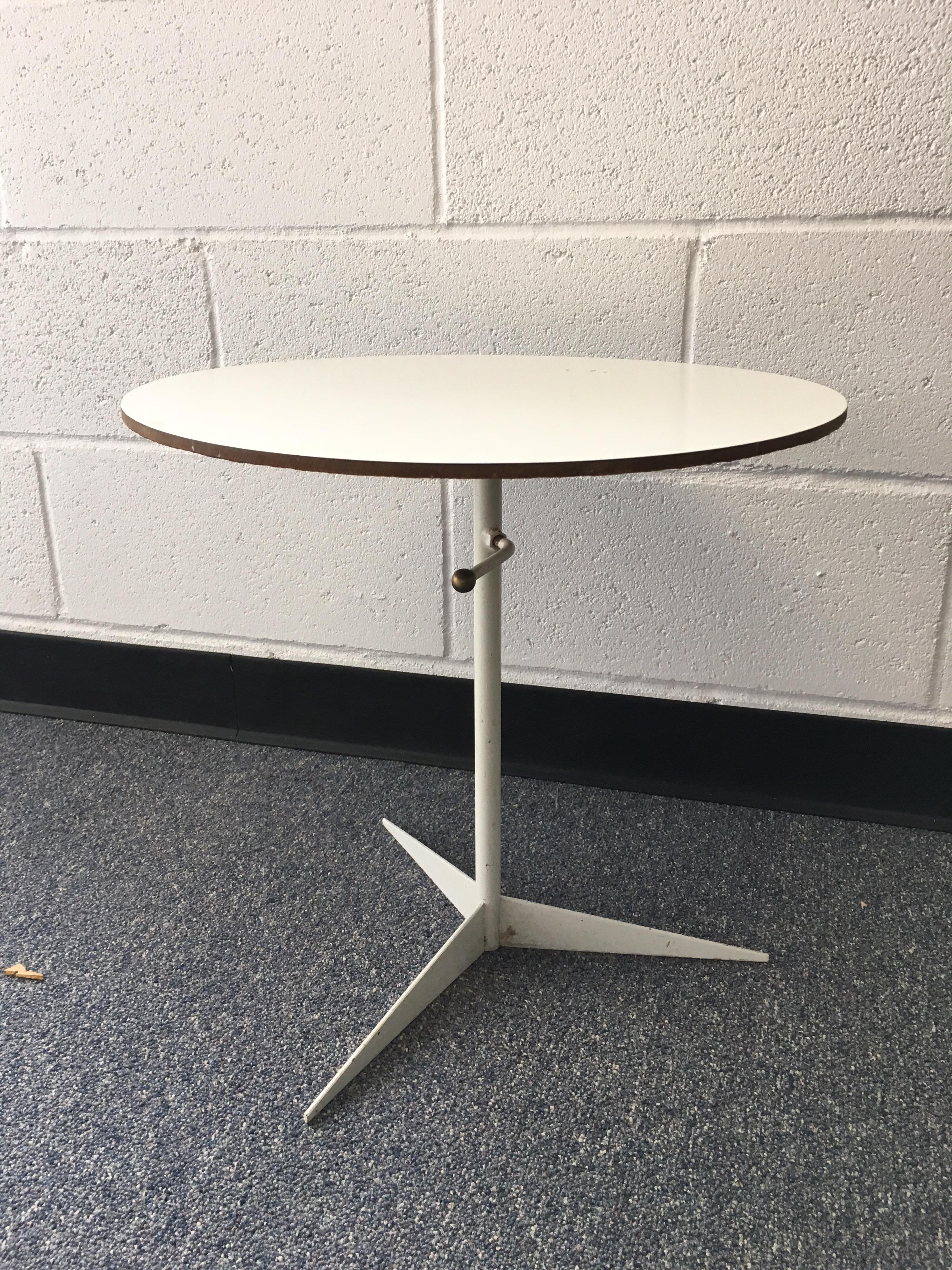 Late 20th century round white tripod table. White metal tripod base with sharp lines. White laminate top. Small lever to adjust height.