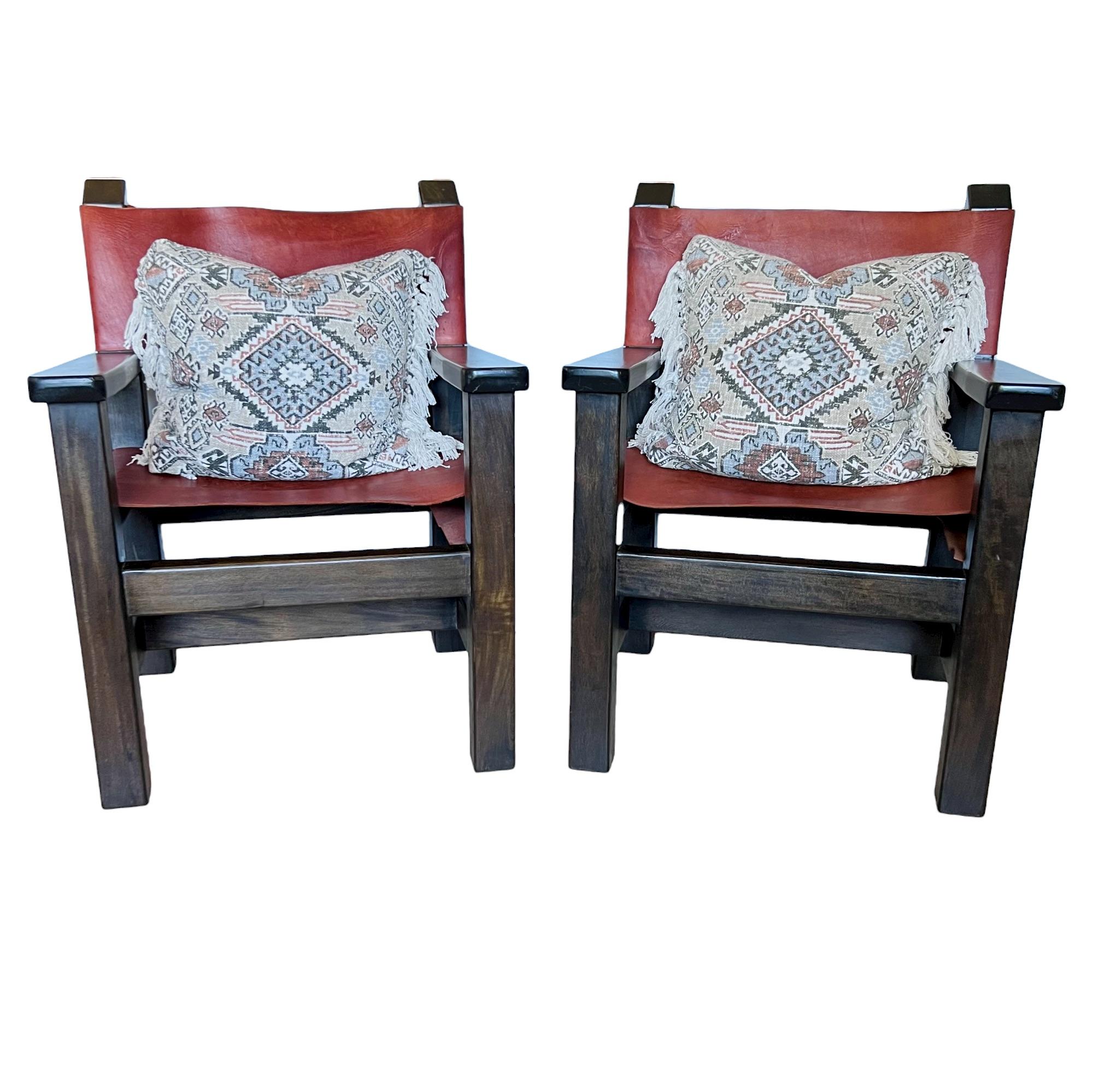 A late 20th century pair of large, sturdy Spanish brutalist director's style armchairs. Dark wood frames with cognac saddle leather chair backs and seats.

Dimensions: 26.75