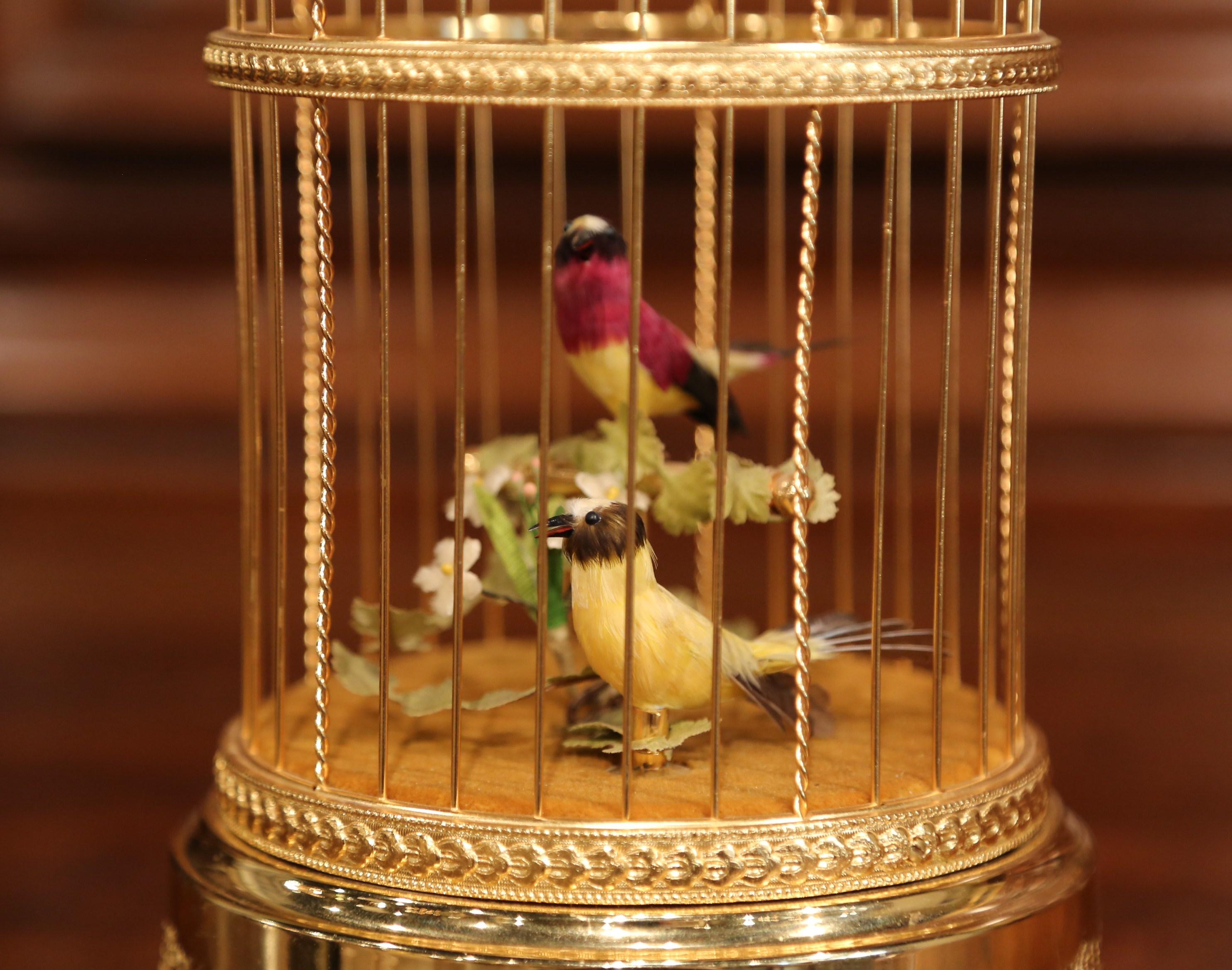 Bring life to your house with this colorful vintage birdcage. Crafted by Reuge Music in Switzerland circa 1980, the cage is cylindrical in shape and topped with a rounded dome. Inside the gilded cage, there are two miniature automaton birds. The
