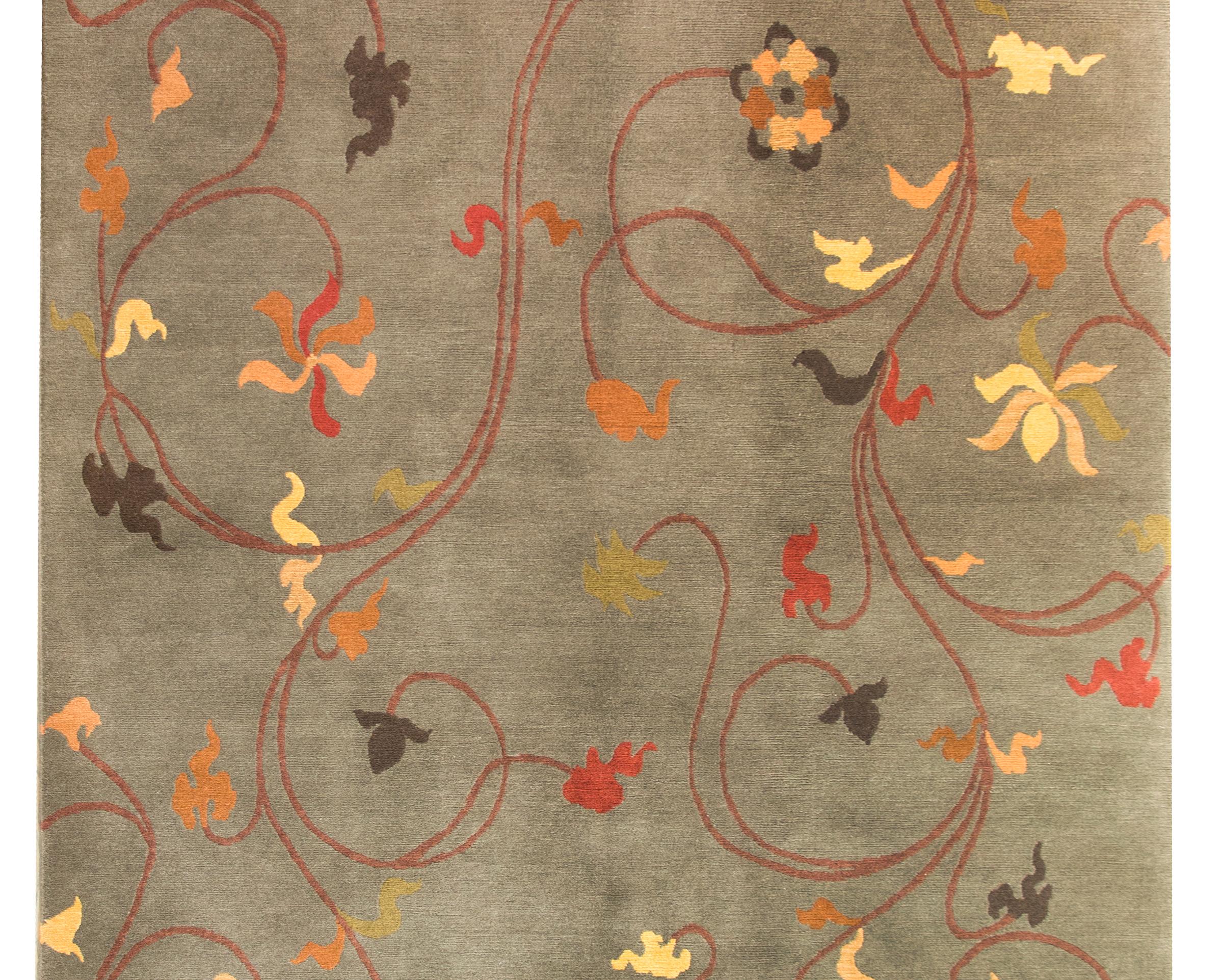 A chic late 20th century Tibetan hand-knotted rug with a gray background and an all-over scrolling vine and stylized flower pattern woven in crimson, pink, cream, orange, and dark gray colors.
