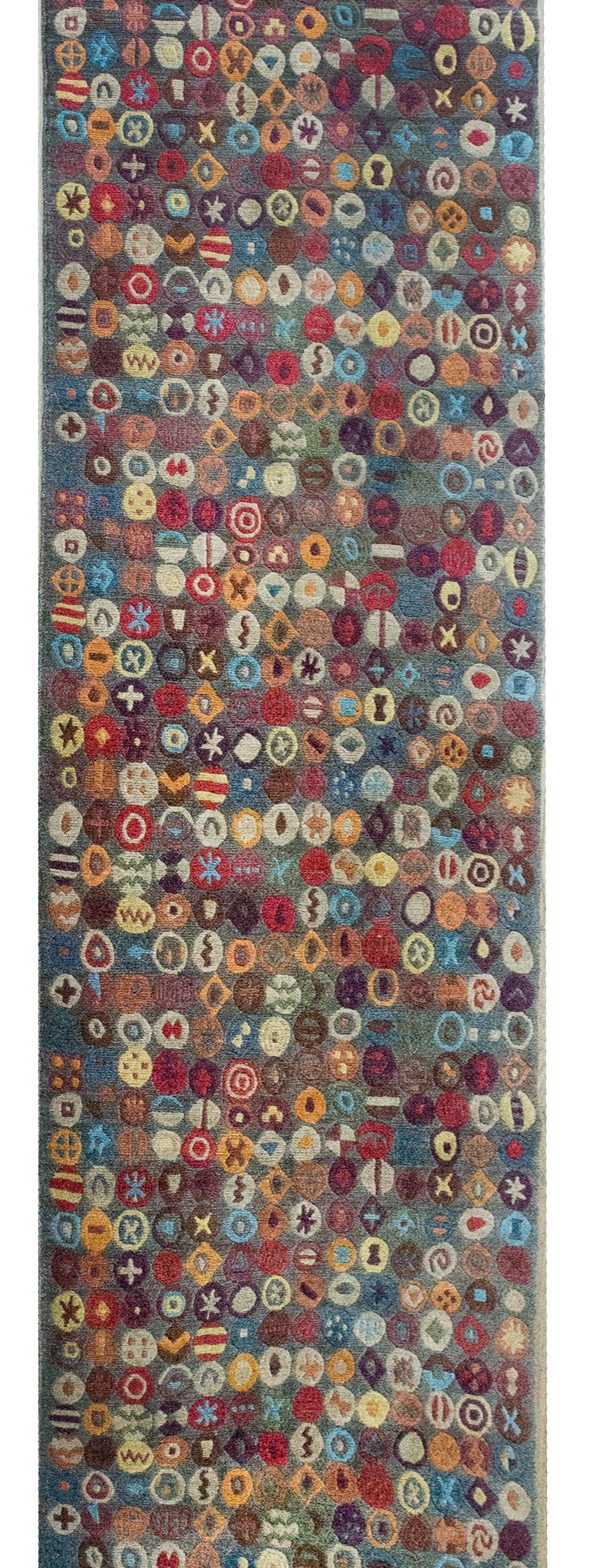 Ce chemin de table tibétain en laine nouée à la main à la fin du XXe siècle est une célébration étonnante de couleurs vibrantes et de motifs complexes. Tissé avec des centaines de petits détails circulaires rappelant les runes anciennes, le motif