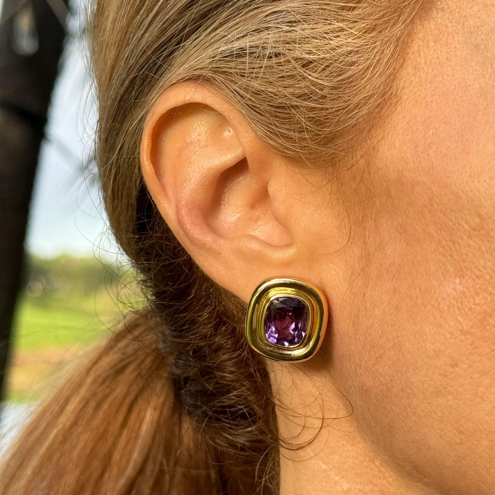 These exquisite 18k yellow gold earrings by Paloma Picasso for Tiffany & Company feature a stunning cushion cut bezel-set amethyst, beautifully highlighting the rich, vibrant purple tones of the gemstone. Each earring measures 18 x 20mm. The bezel