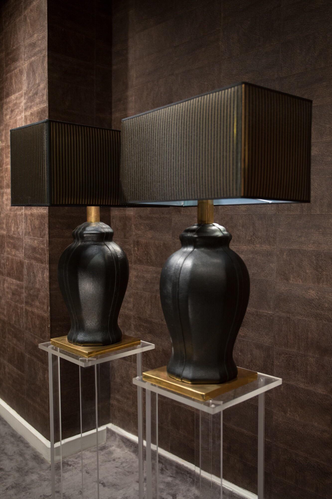 In addition to their very beautiful shapes, what characterizes this set of two lamps, is their prestigious black leather coating.
The base is made in gilt brass.
The unique atmosphere produced by the two lamps is due also to the fabric and