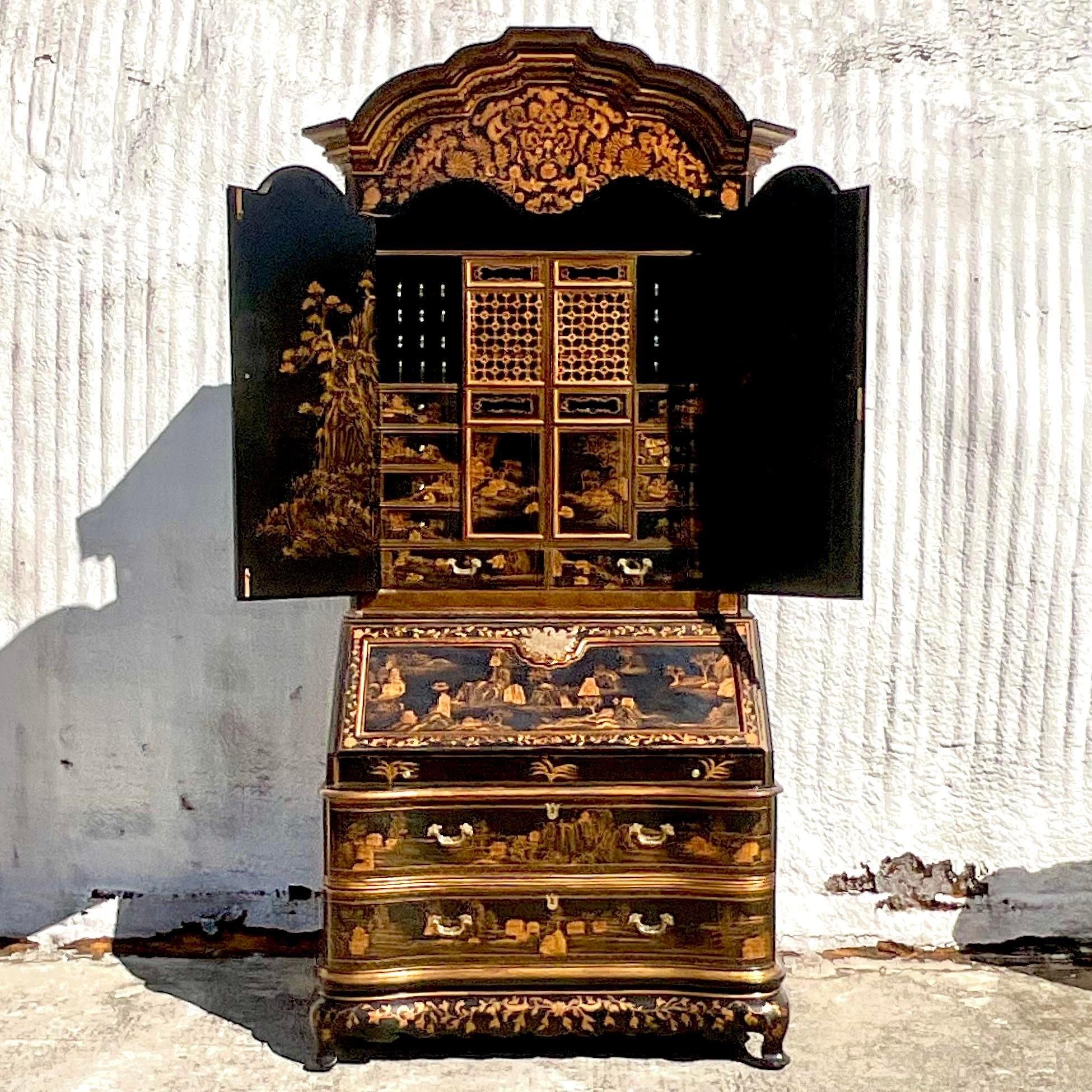 A spectacular vintage Asian secretary desk. A chic black lacquered cabinet with hand painted gilt pastoral scenes. The most beautiful collection of drawers and cabinets. Flip down desk top and rolling front design. Acquired from a Palm Beach estate.