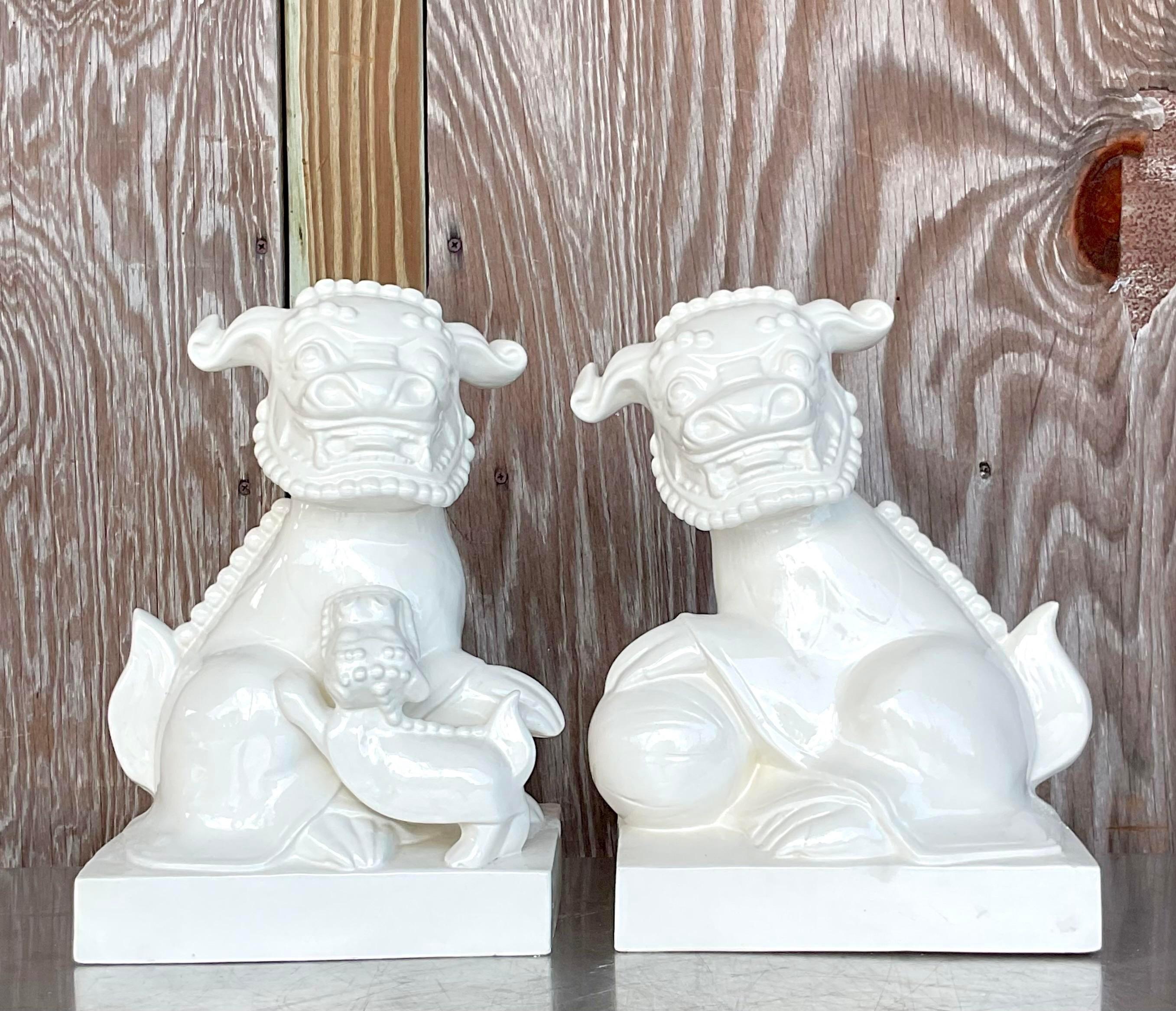 A fabulous pair of vintage Asian foo dogs. Chic white glazed ceramic finish and a playful pose. Acquired from a Palm Beach estate.