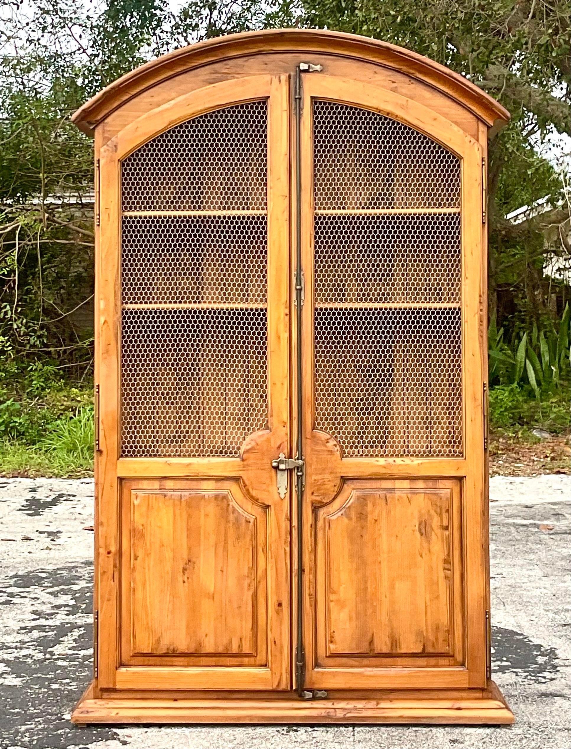A stunning vintage a boho armoire. Monumental in size and drama. A chic arched design with inset with mesh doors. Perfect closed, but also gorgeous left open. Acquired from a Palm Beach estate.
