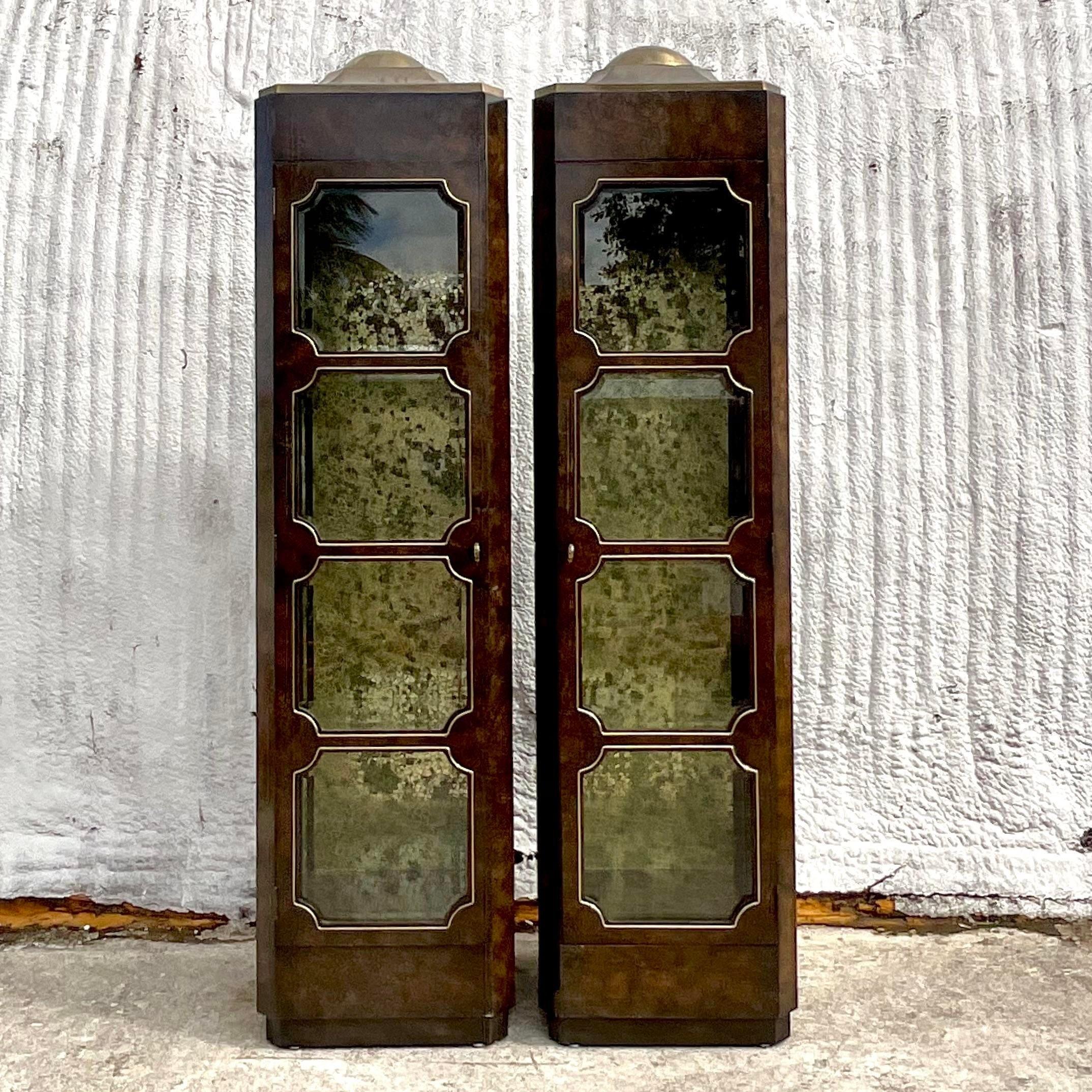 A stunning pair of vintage Boho etagere. Done in the manner of the iconic Mastercraft group. A chic octagon shaped tall cabinet with inset glass panels. A mottles gold leaf paper back panel adds to the drama. Faceted brass rocket top. Acquired from