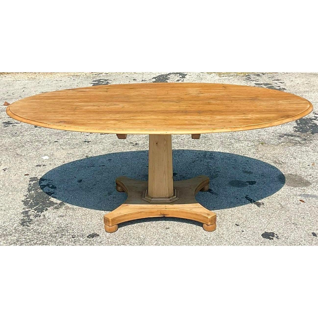 A fantastic vintage Boho pine dining table. A chic patinated finish for that rustic look. A rare elliptical shape with a center pedestal. Acquired from a Palm Beach estate.