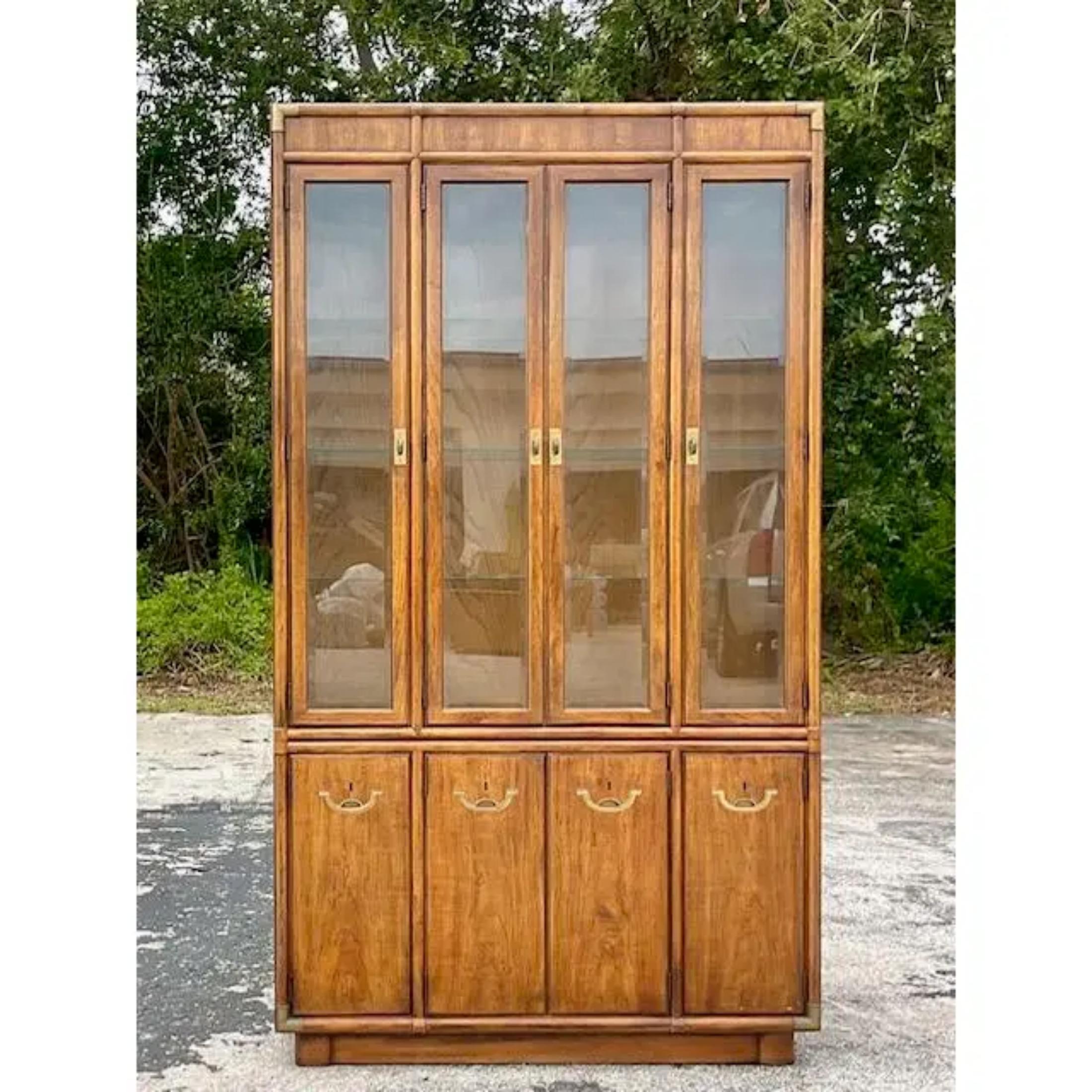 A fabulous vintage Boho china cabinet. Made by the iconic Drexel group and tagged inside the drawer. Beautiful burnished brass campaign hardware. Interior glass shelving and a wood back panel. Acquired from a Palm Beach estate.