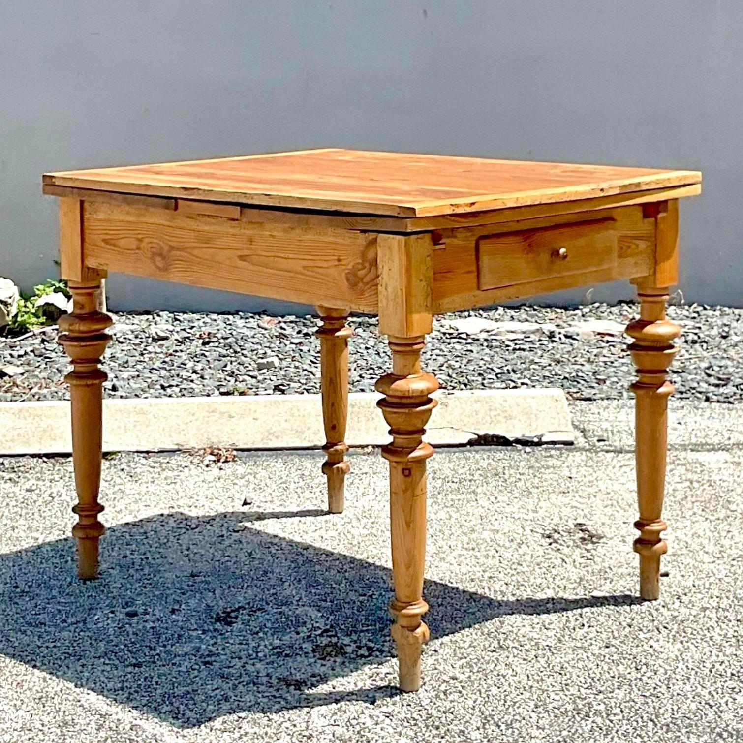 A fabulous vintage Boho dining table. A chic rustic pine construction with hand turned legs. A patinated top with an authentic look. Two concealed leaves pull out for an extended surface. Perfect as a small table, desk or a kitchen island and then