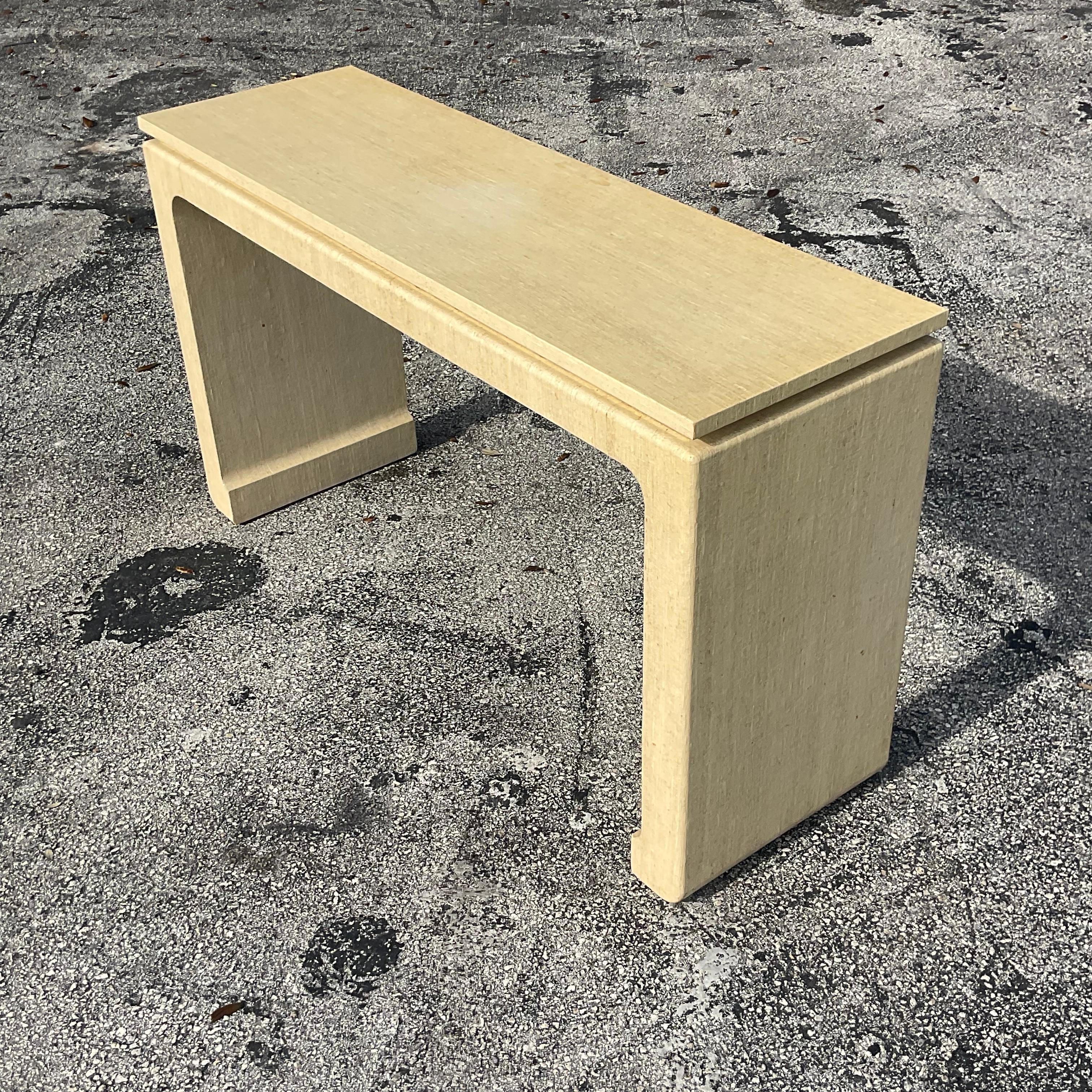 A fantastic vintage Boho console table. A chic wrapped Grasscloth table with a floating top and a brass band below the top. Acquired from a Palm Beach estate.