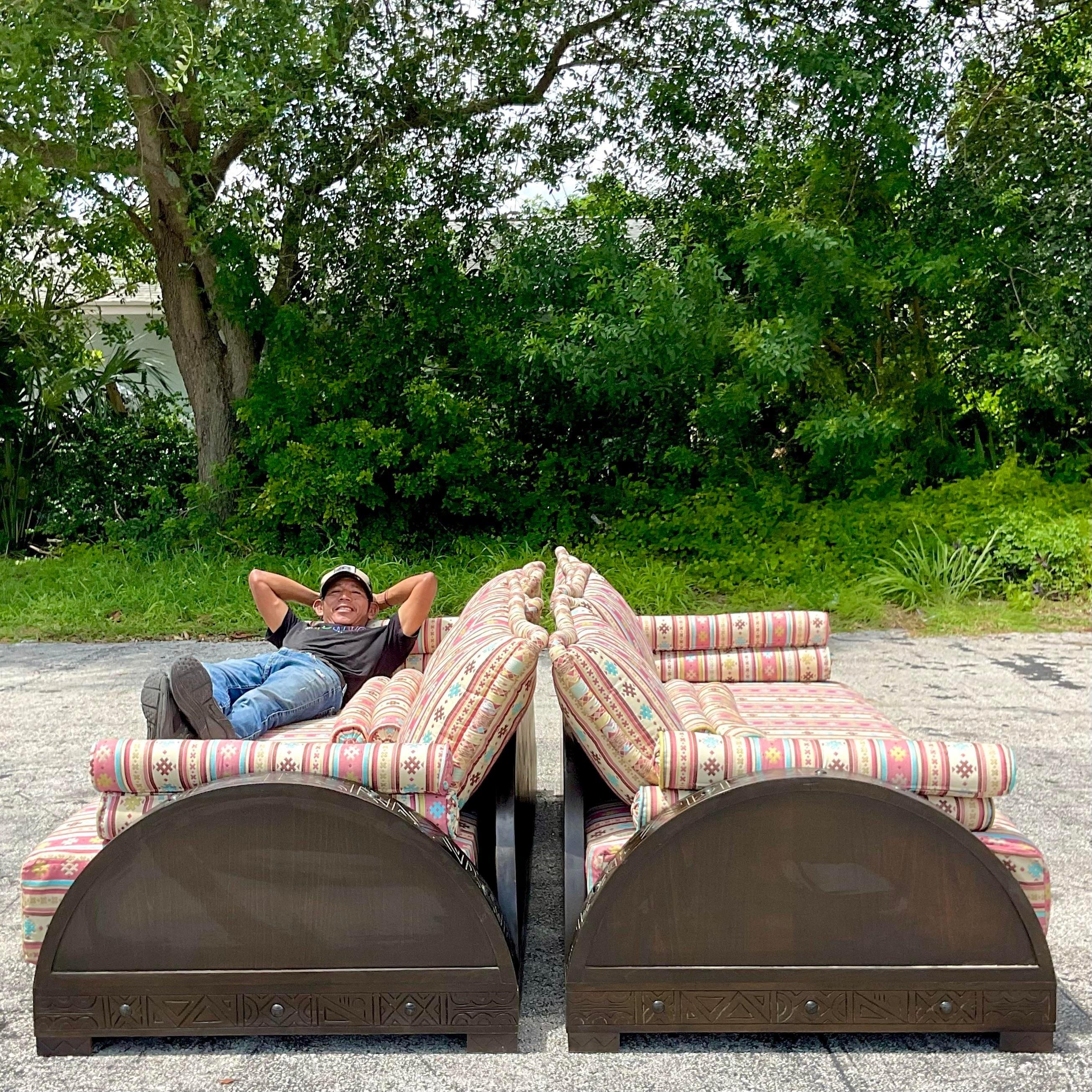 A fabulous pair of vintage Boho sofas. A chic Moroccan style with hand carved detail. A fabulous striped jacquard upholstery with coordinating bolster pillows. Acquired from a Palm Beach estate.