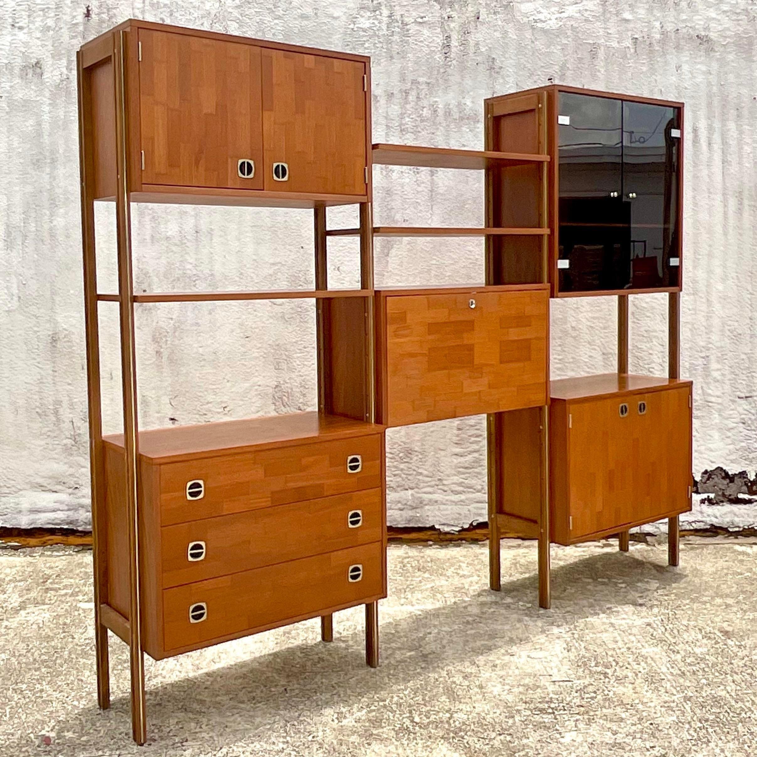 A fantastic vintage Boho wall unit. Done after the Ello group. Beautiful free standing unit that has adjustable shelving and cabinets. Smoked glass doors on one set with teak panels on the others. Move them to suit your project. Breaks down into two