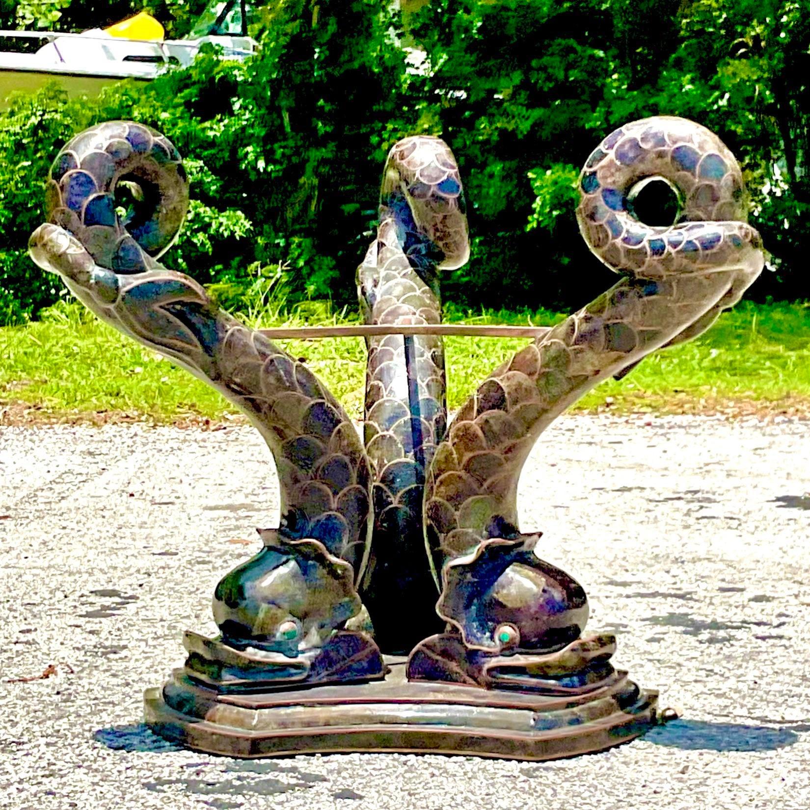 A truly extraordinary vintage Boho dining table. A chic Dolphin tripod done in tessellated stone and brass inlay. The most amazing mottled greenish brown color. A stunning custom notched and beveled glass top. Acquired from a Palm Beach estate. 
