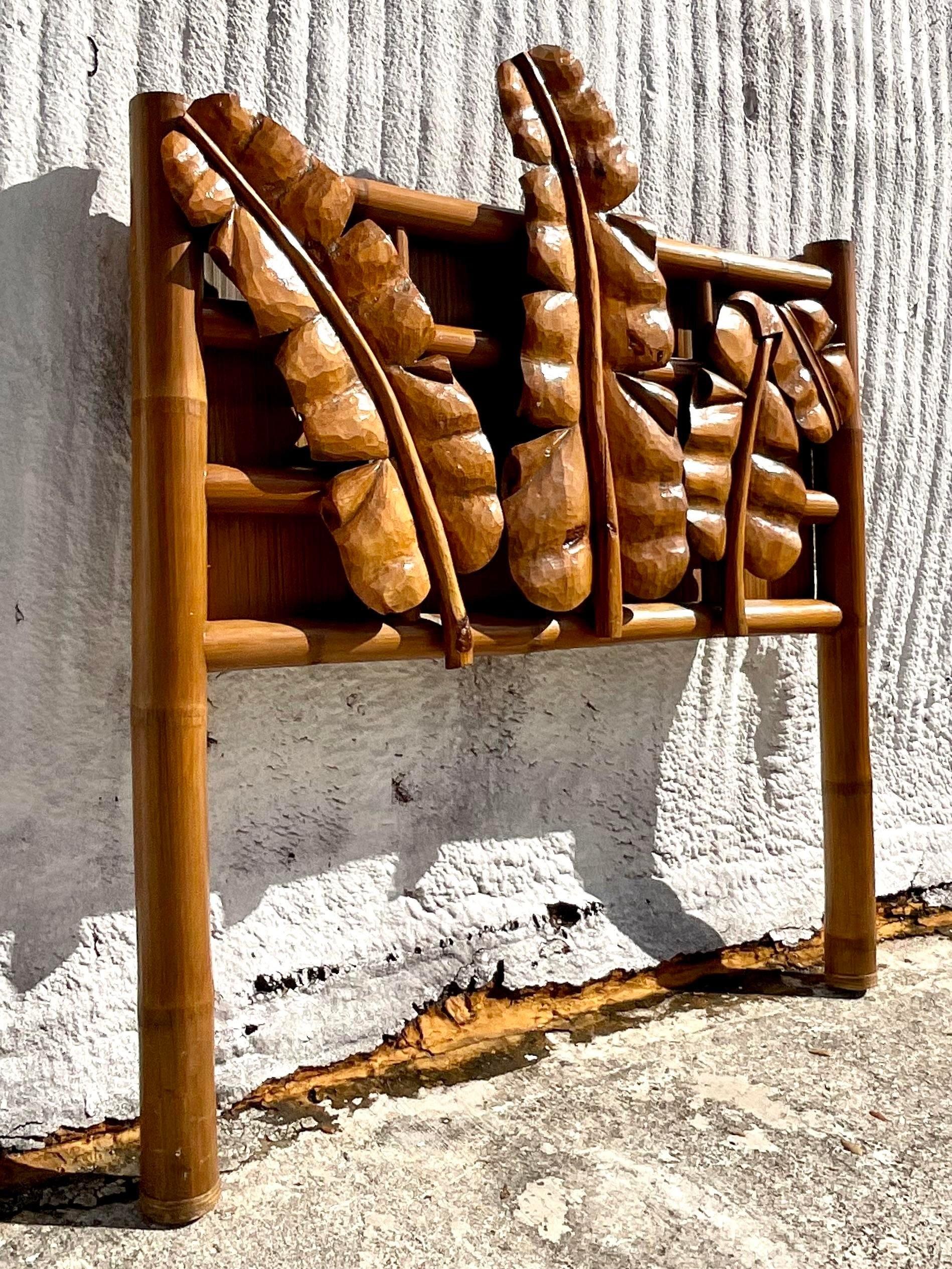 A fabulous vintage Coastal Queen headboard. A chic carved banana leaf design on a heavy bamboo frame. Acquired from a Palm Beach estate.