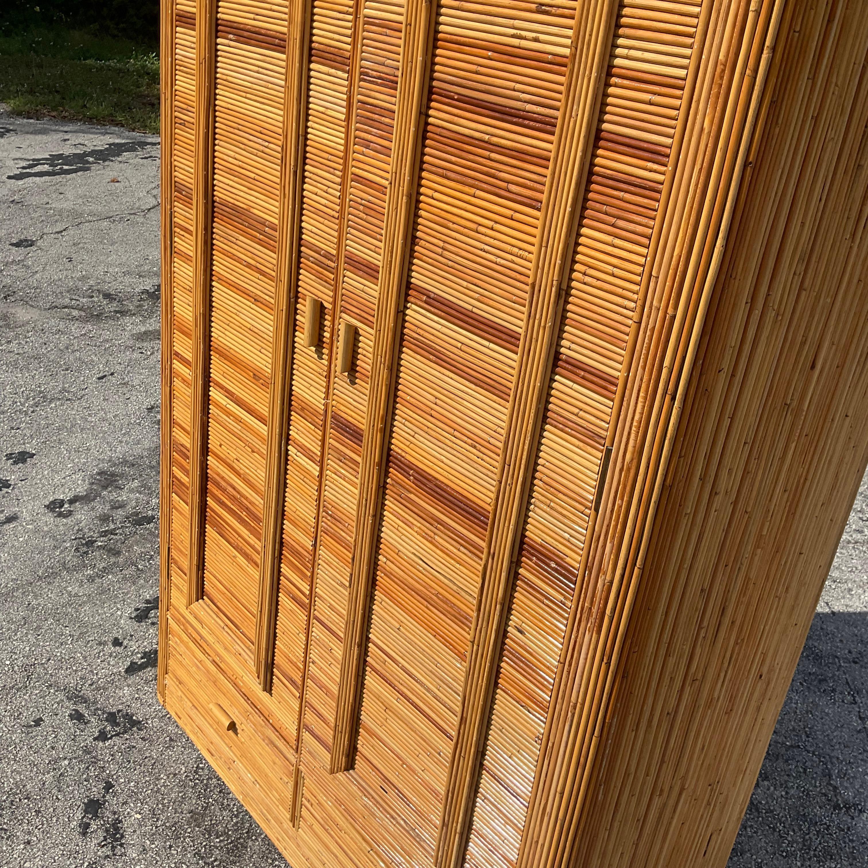 A fantastic vintage Coastal armoire. A chic pencil reed cabinet with a fabulous arched motif. A Double interior hang bar for lots of great storage. Acquired from a Palm Beach estate