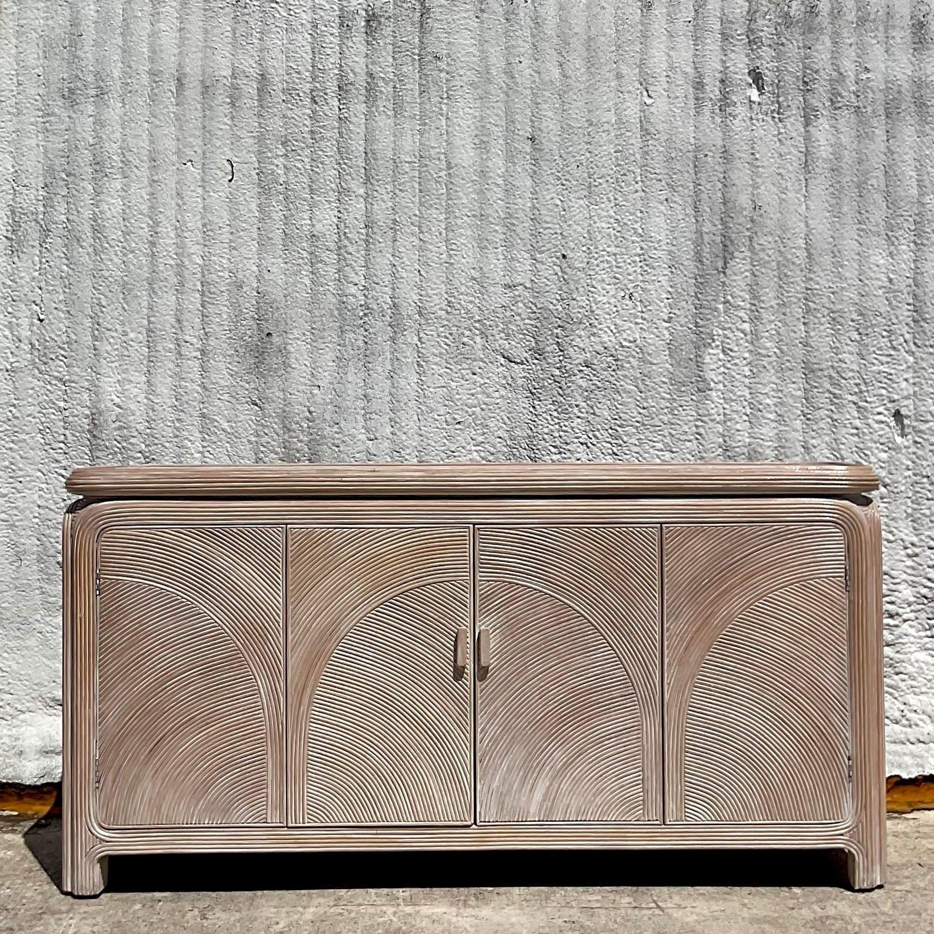 A fantastic vintage Costal credenza. A chic arched pencil reed frame with a gorgeous washed finish. Lots of great interior storage. Acquired from a Palm Beach estate
