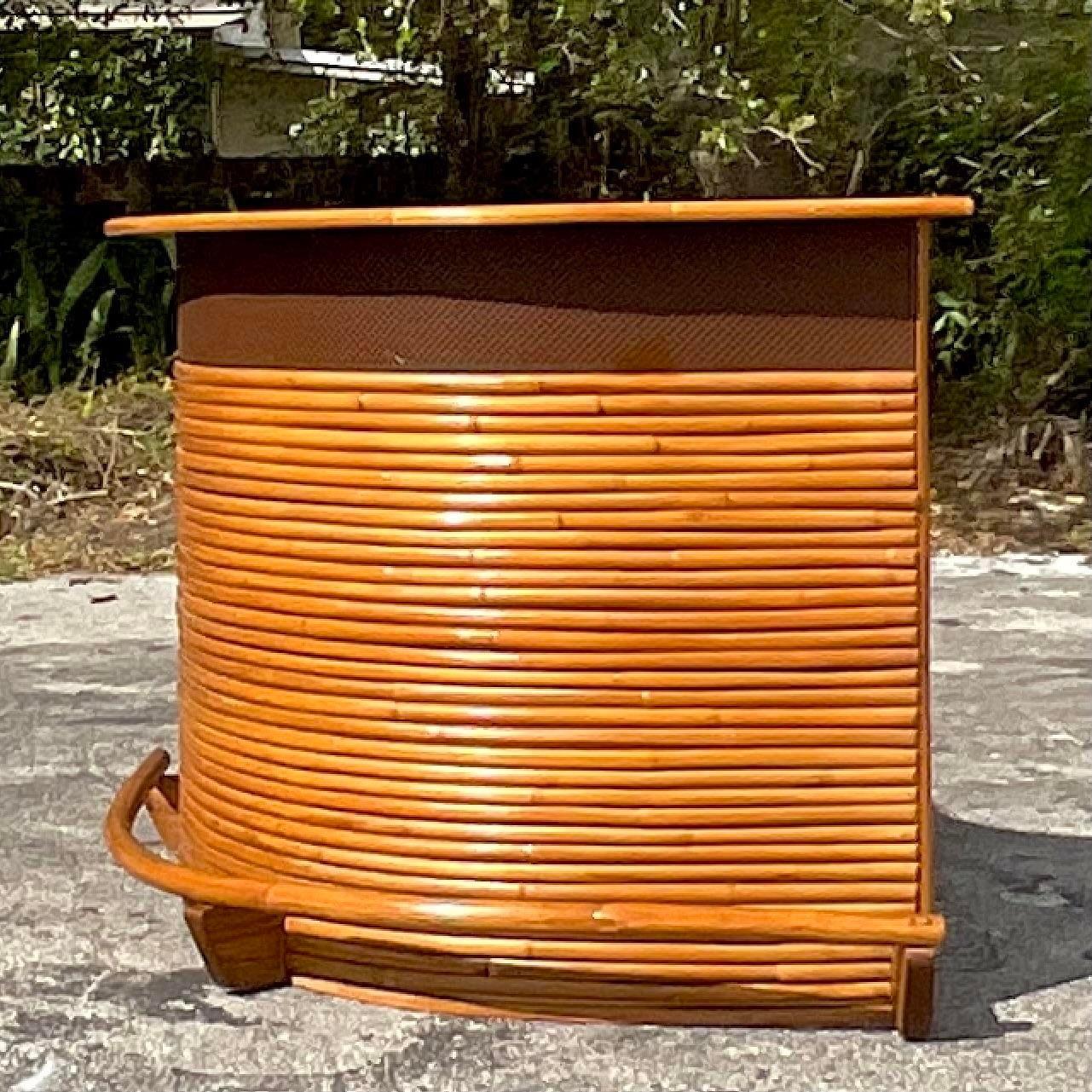 A fabulous vintage Coastal dry bar. A chic bent rattan in a boomerang shape. Gorgeous retro laminate top in great shape. Running rail along the bottom. Lots of great storage behind. Acquired from a Palm Beach estate.