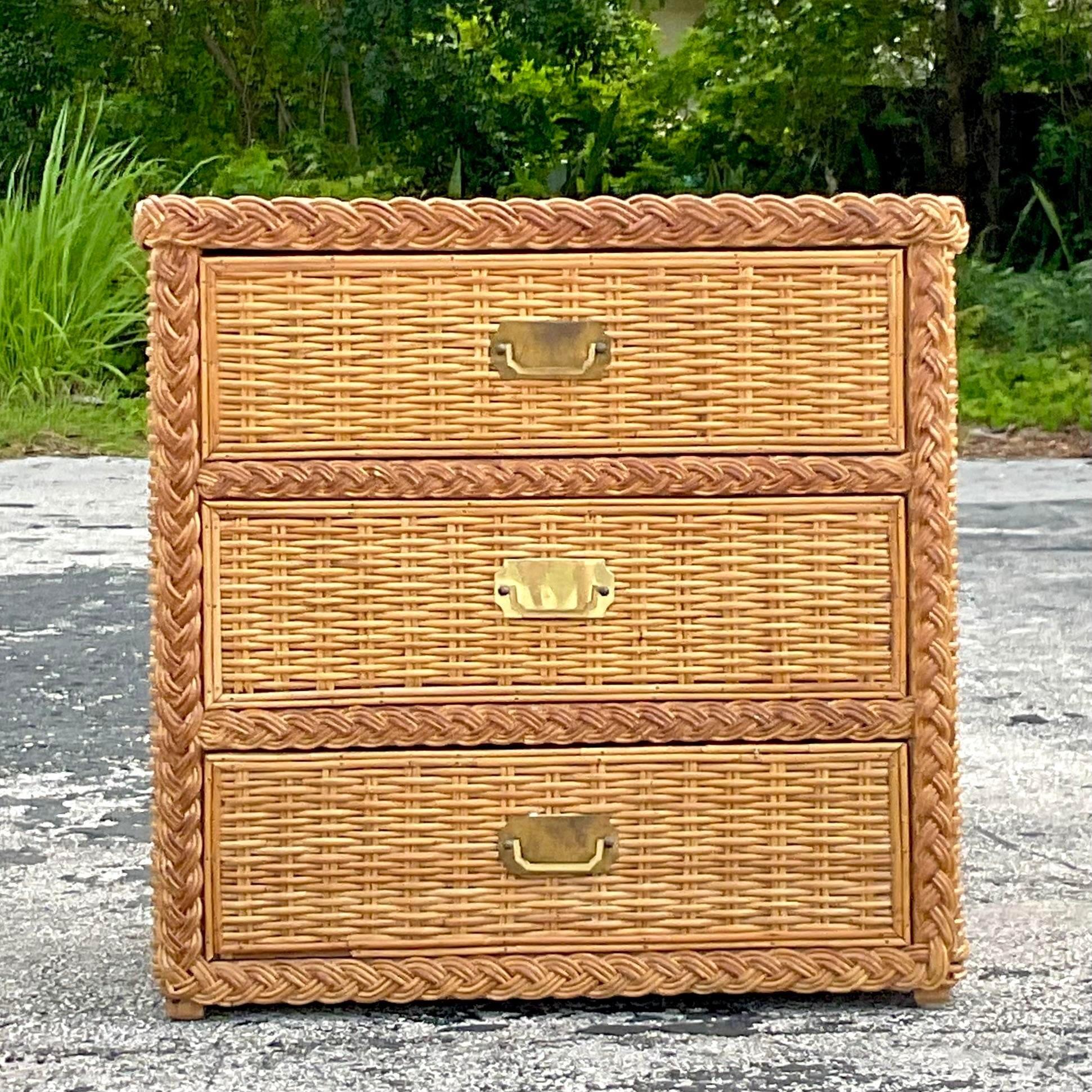 A fantastic vintage Coastal chest of drawers. A chic braided rattan trim on a thick woven rattan design. Brass Campaign hardware. Acquired from a Palm Beach estate.