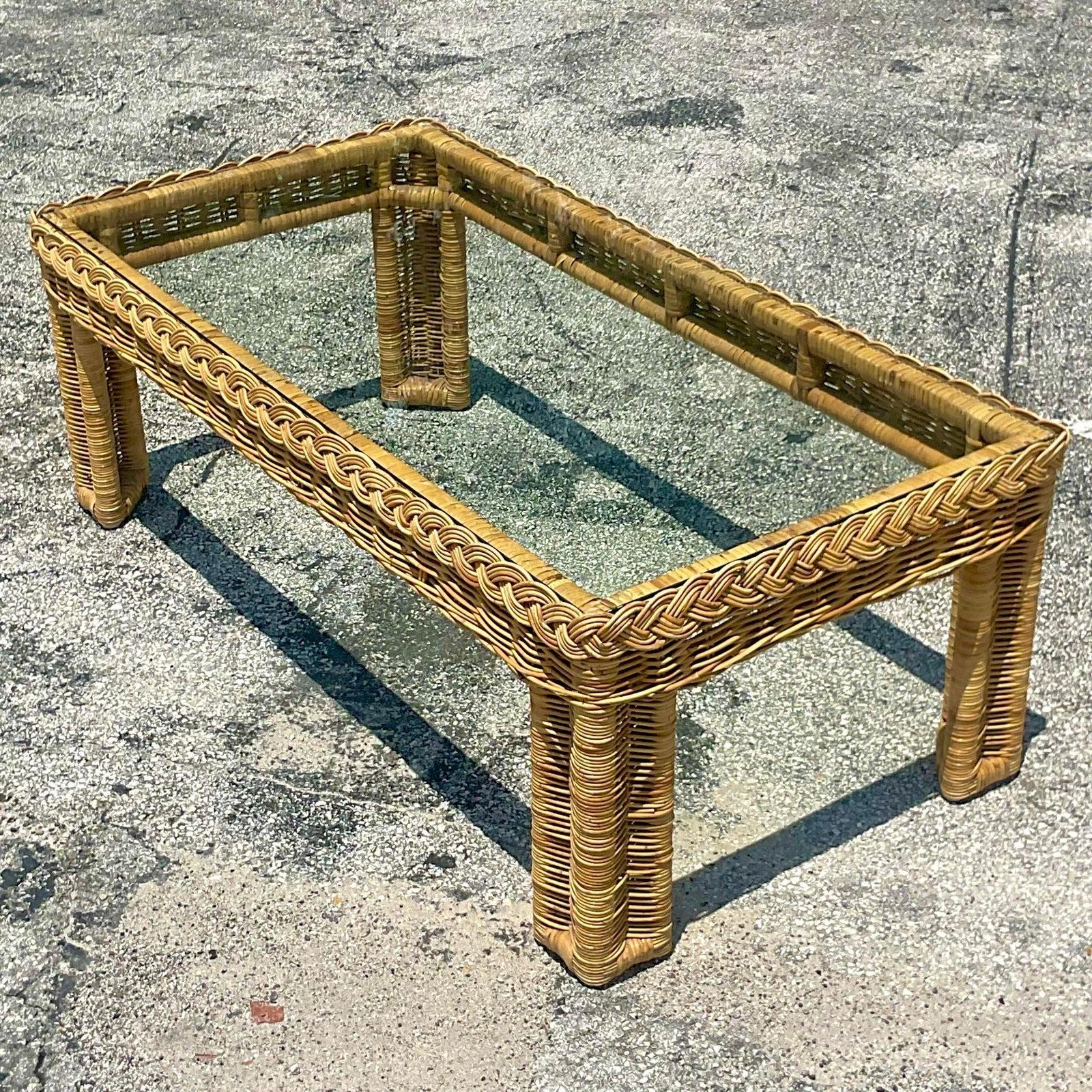 A fabulous vintage Coastal coffee table. A classic rectangle shape with inset glass top. Chic braided rattan trim along the edge. Acquired from a Palm Beach estate.