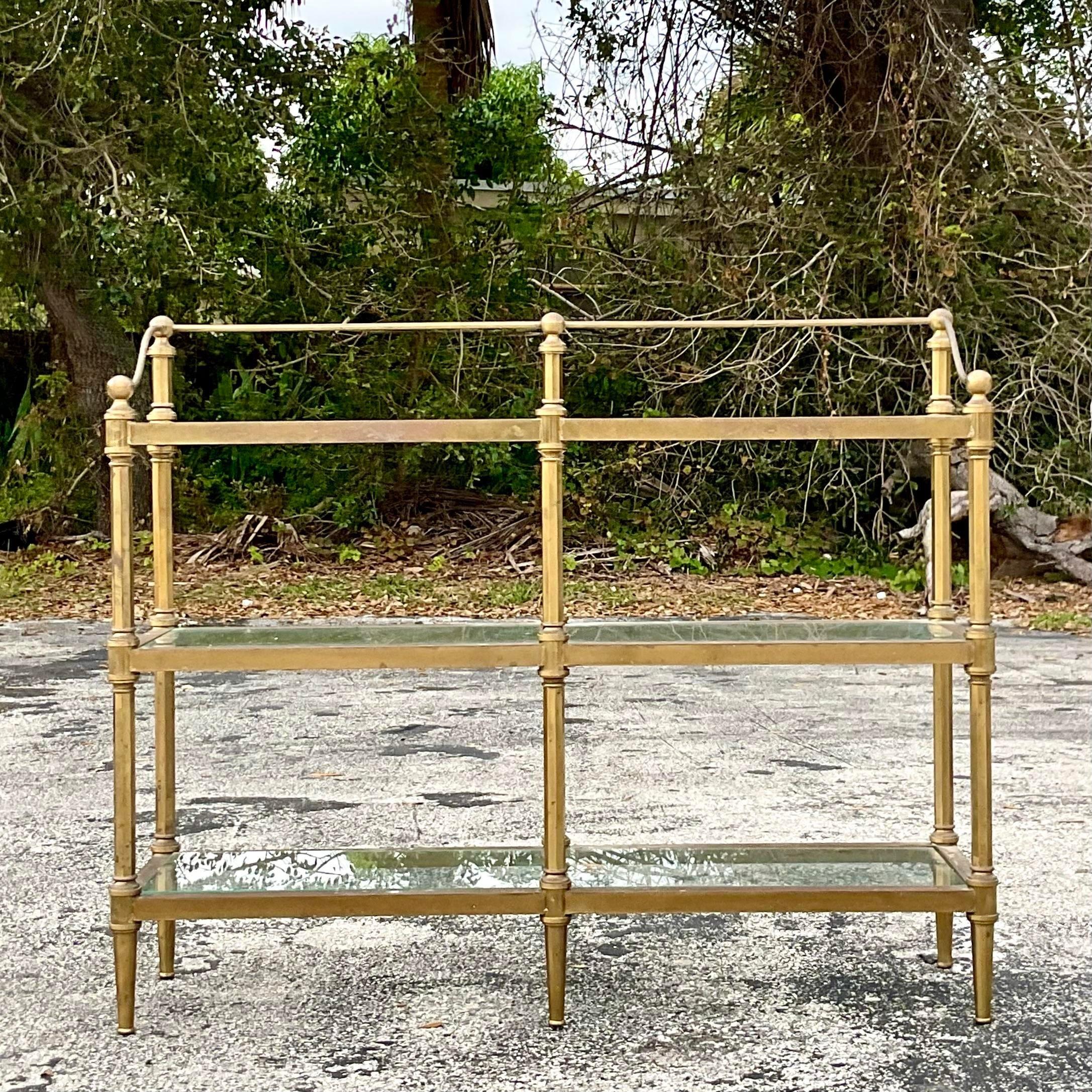 A brilliant vintage Regency low etagere. A chic brass frame with inset glass shelves. Perfect as an etagere, but also would make the most gorgeous dry bar. You decide. Acquired from a Palm Beach estate.