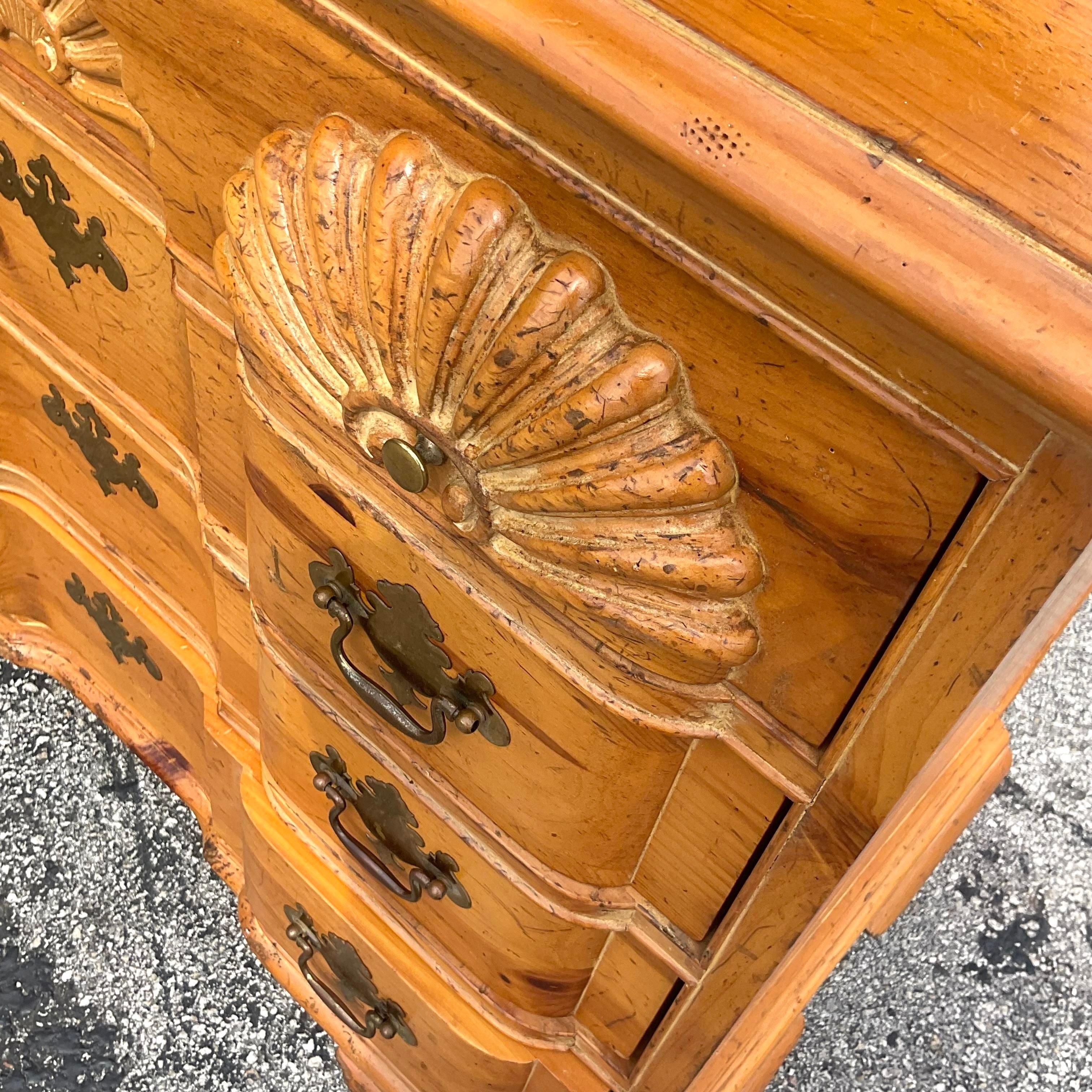 Elevate your coastal-inspired decor with our Vintage Coastal Carved Clam Shell Knotty Pine Chest Of Drawers. Crafted with meticulous attention to detail, this unique piece combines the rustic charm of knotty pine with the whimsical beauty of a