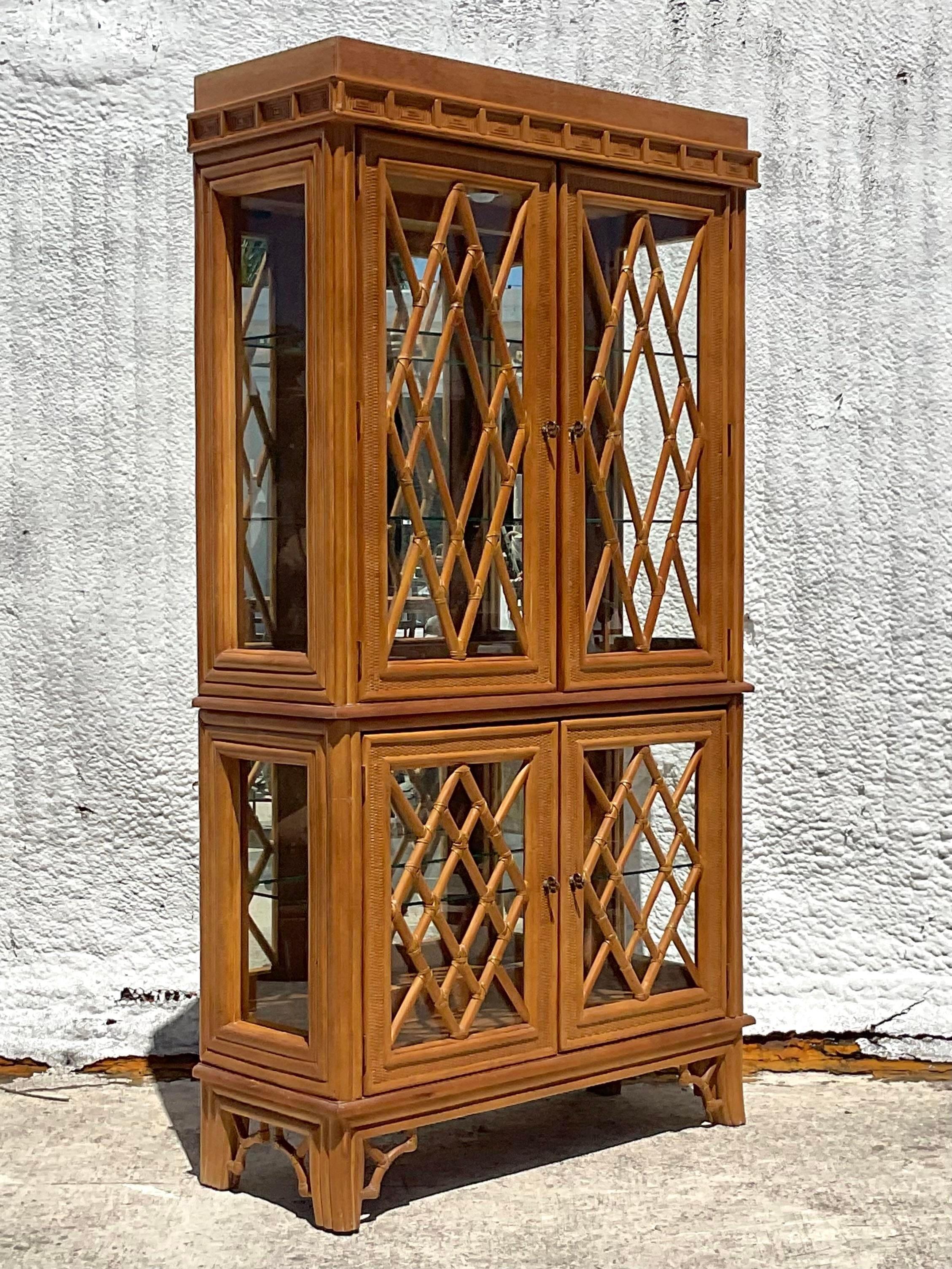 A fabulous vintage Coastal display cabinet. A chic Chinese Chippendale design in the mullions. Inset glass shelves, interior lights and mirrored back walls. Acquired from a Palm Beach estate.