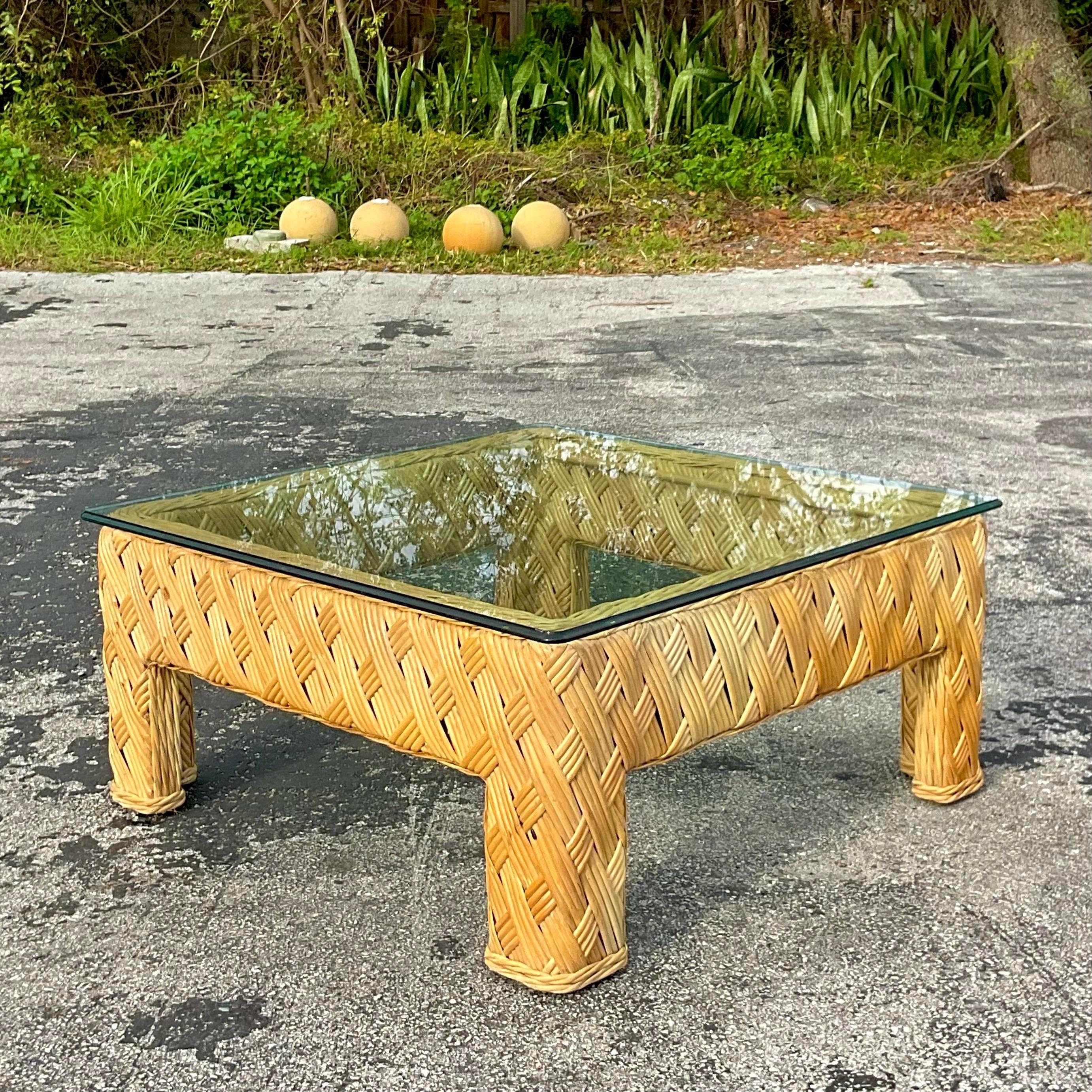 A stunning vintage Coastal coffee table. A chic crosshatch woven rattan in a classic Parsons shape. Glass top makes it easy to see the beautiful interior weave. Acquired from a Palm Beach estate.