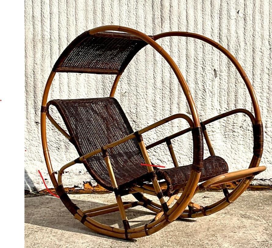 A fantastic vintage Coastal Italian wrapped rattan rocking chair. After the “Donaoldo” chair designed by Franco Bettonica. A chic bamboo frame with a woven rattan seat and canopy. Acquired from a Palm Beach estate
