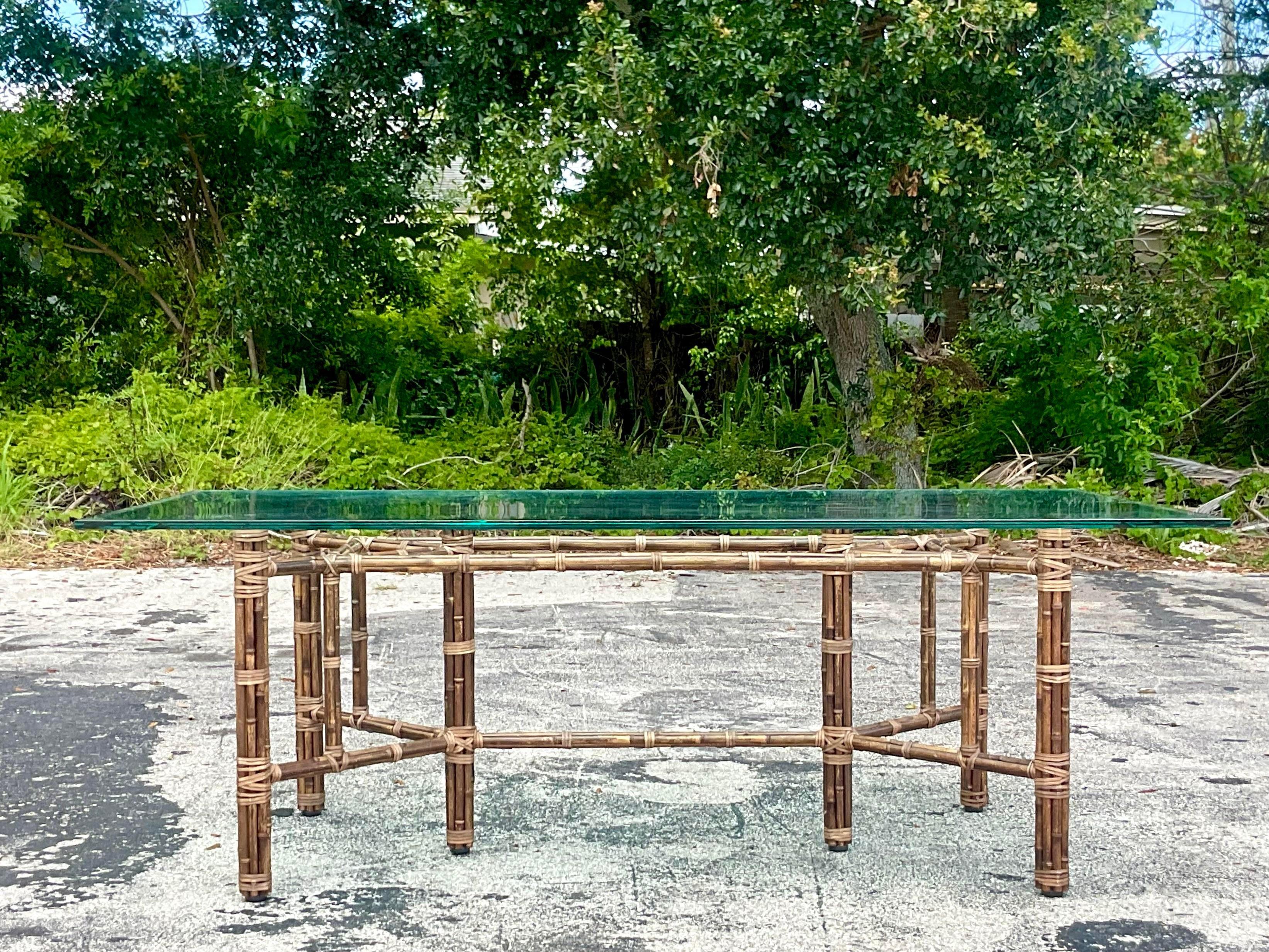 A fabulous vintage Costal bundled bamboo dining table. Made by the iconic McGuire group and tagged with the logo on the frame. Heavy glass top rests on the pedestal. Acquired from a Palm Beach estate.