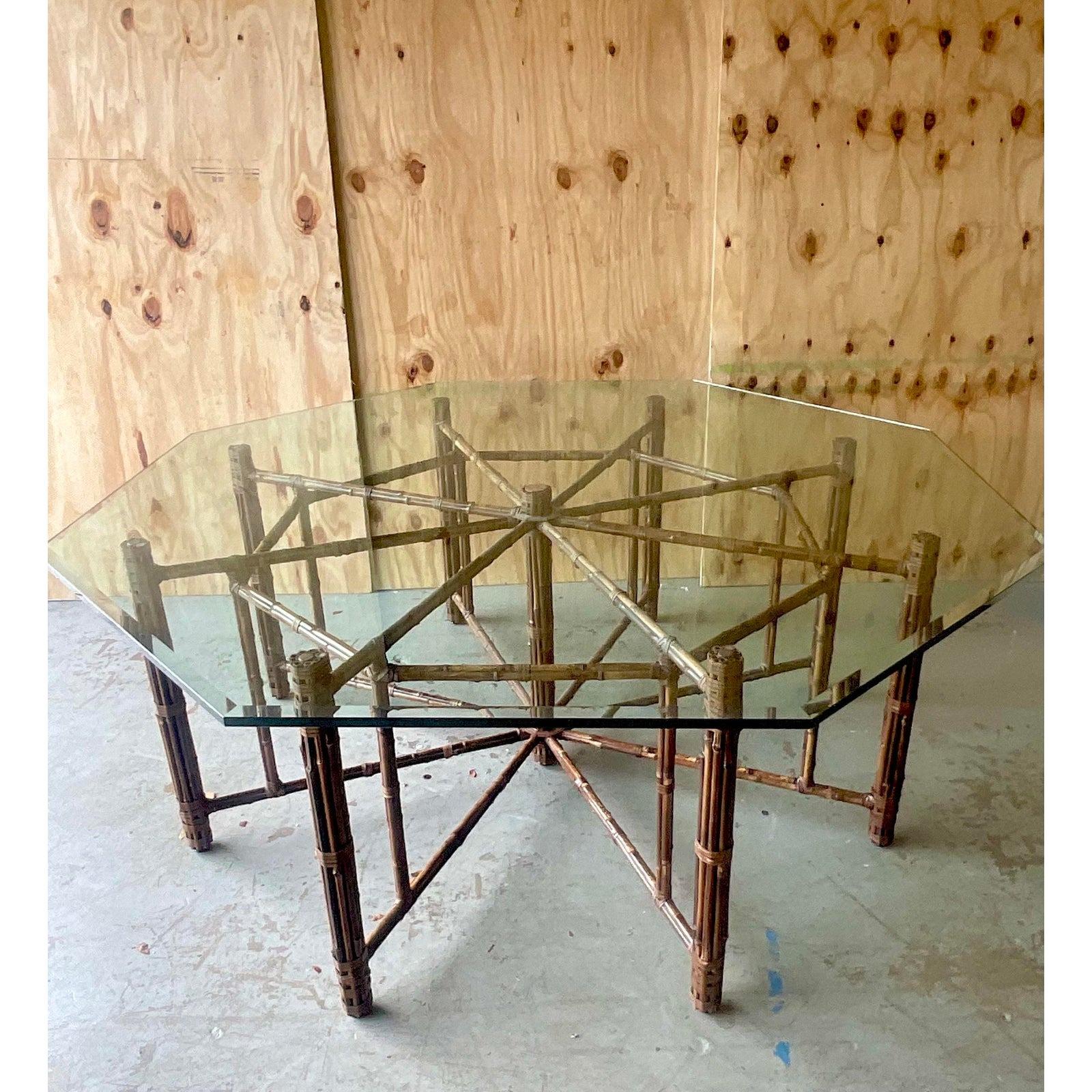 A fantastic vintage Coastal dining table. Made by the iconic McGuire group and tagged on the bottom. Beautiful bundled rattan over a metal frame. An octagon shaped glass top. Acquired from a Boca Raton estate