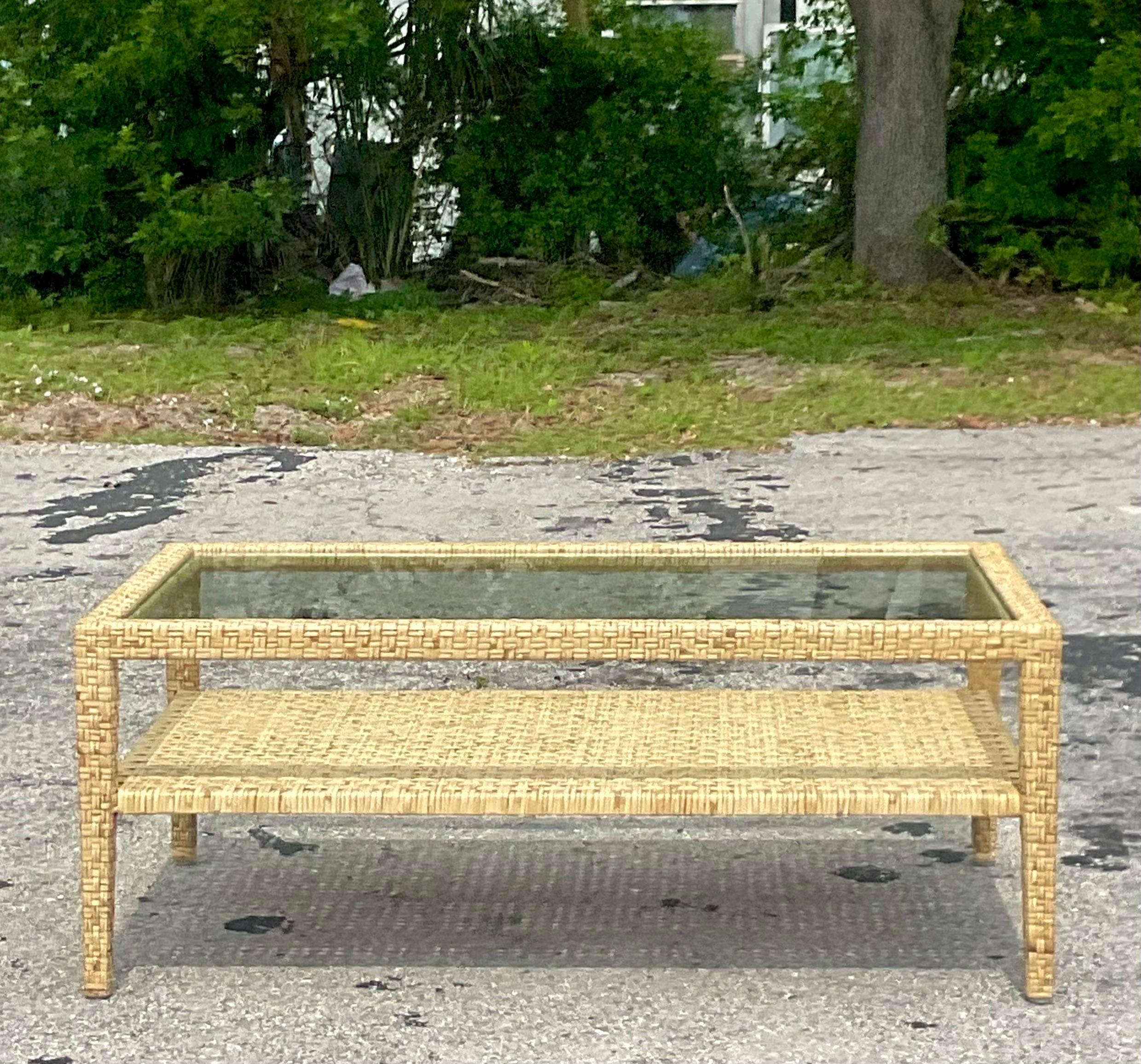 A fabulous vintage Coastal coffee table. Made by the iconic McGuire group. A fabulous limited edition design with woven wide ribbon rattan. Inset glass top. Tagged with the logo. Acquired from a Palm Beach estate.