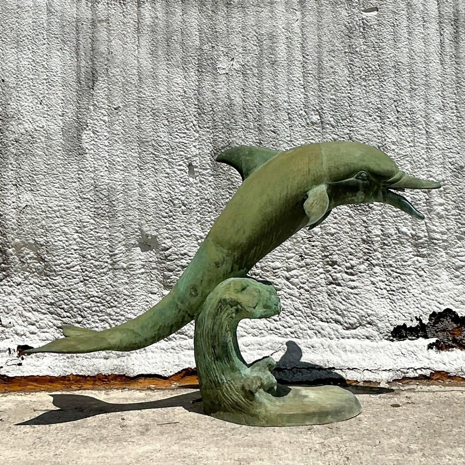 Créez un point focal captivant avec cette impressionnante sculpture de dauphin vintage, réalisée en métal coulé, probablement en bronze, et finie avec une belle patine vert-de-gris. Capturant la grâce dynamique d'un dauphin sautant sur des vagues