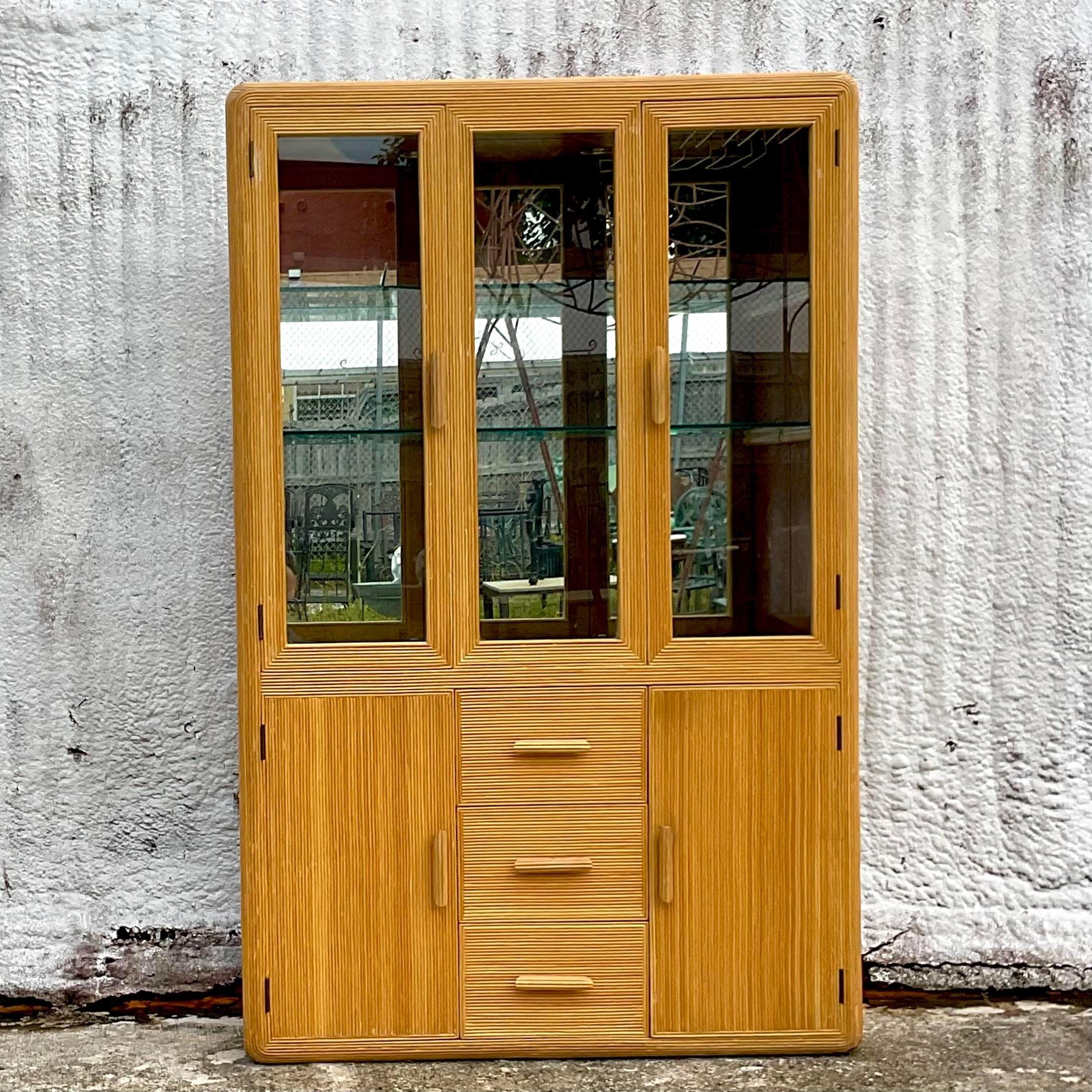 A fabulous vintage Boho China cabinet. A chic pencil reed frame with inset glass doors above. Lots of great storage below. Mirrored back panel to add light to your space. Two interior lights. Acquired from a Palm Beach estate.