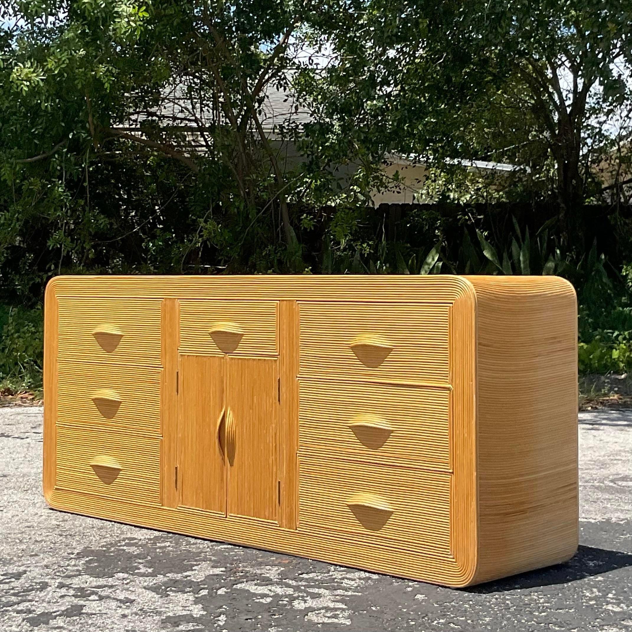 Incredible vintage Coastal pencil reed waterfall credenza. Beautiful blonde color reed with seven drawers and center shelve storage. Acquired from a Palm Beach estate.
