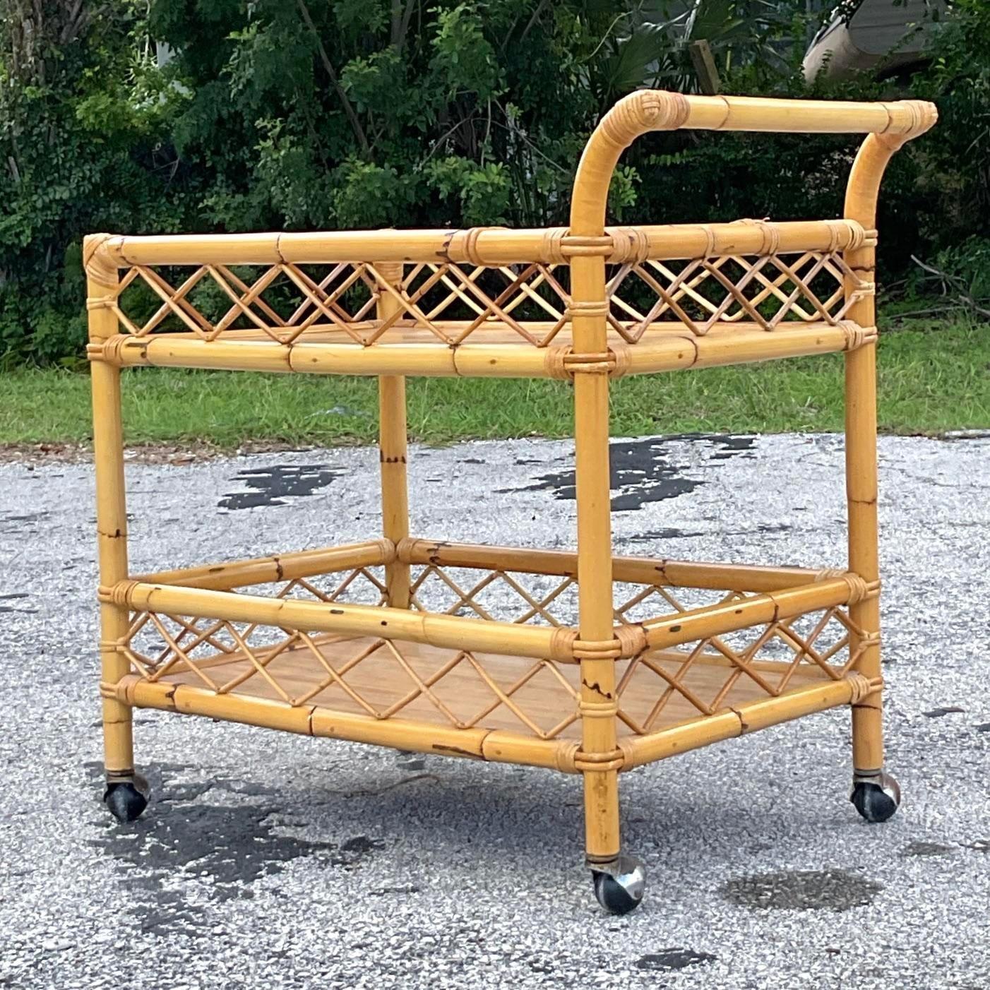 A fabulous vintage Coastal bar cart. A chic wrap around trellis deign on a rolling rattan frame. Laminate shelving make this cart both beautiful and durable. Acquired from a Palm Beach estate.