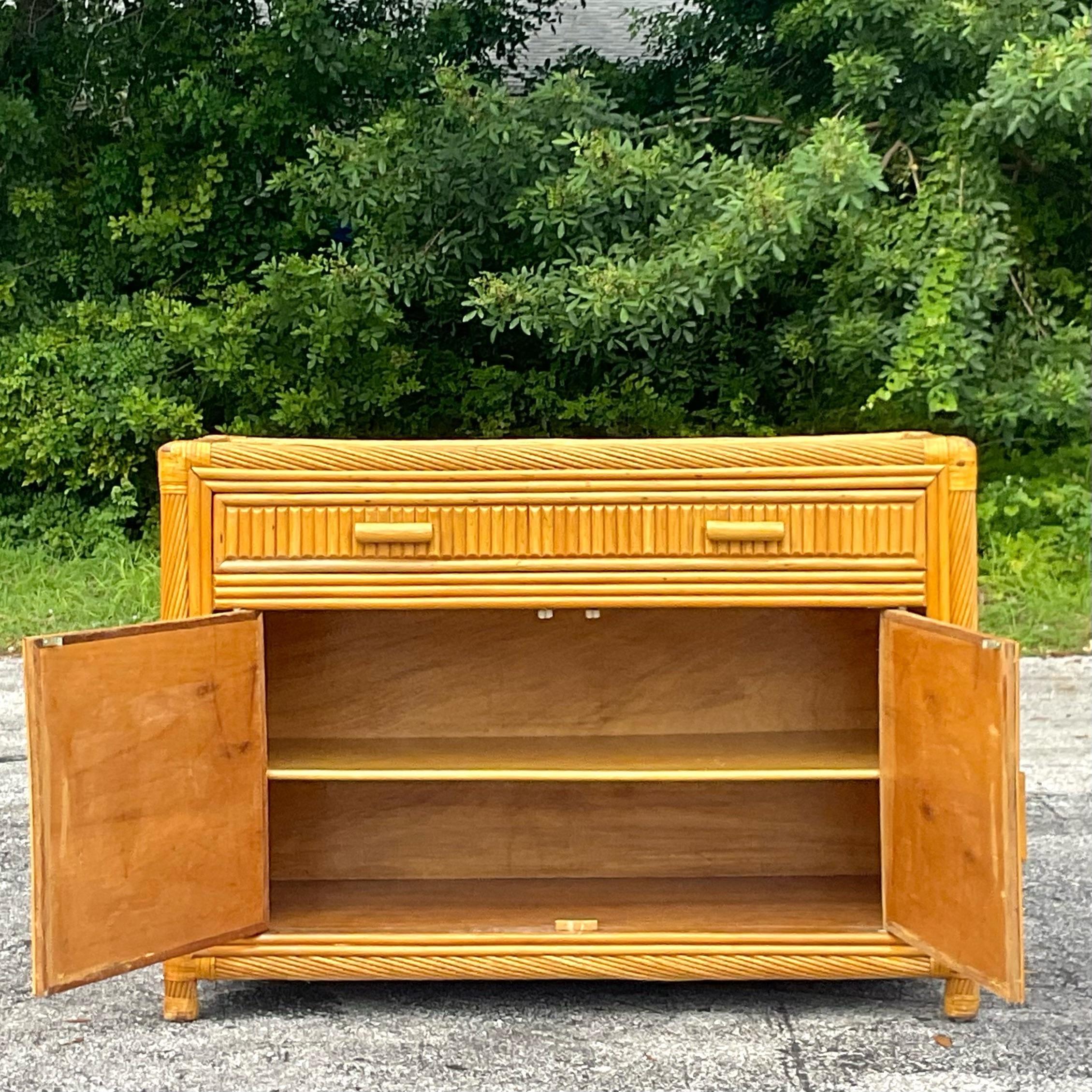 Golden gorgeous split bamboo credenza with swirl detailed trim around the edges. Add glamor and amazing storage to any space. Lots of great storage below and woven rattan on top. Acquired from a Palm Beach estate.