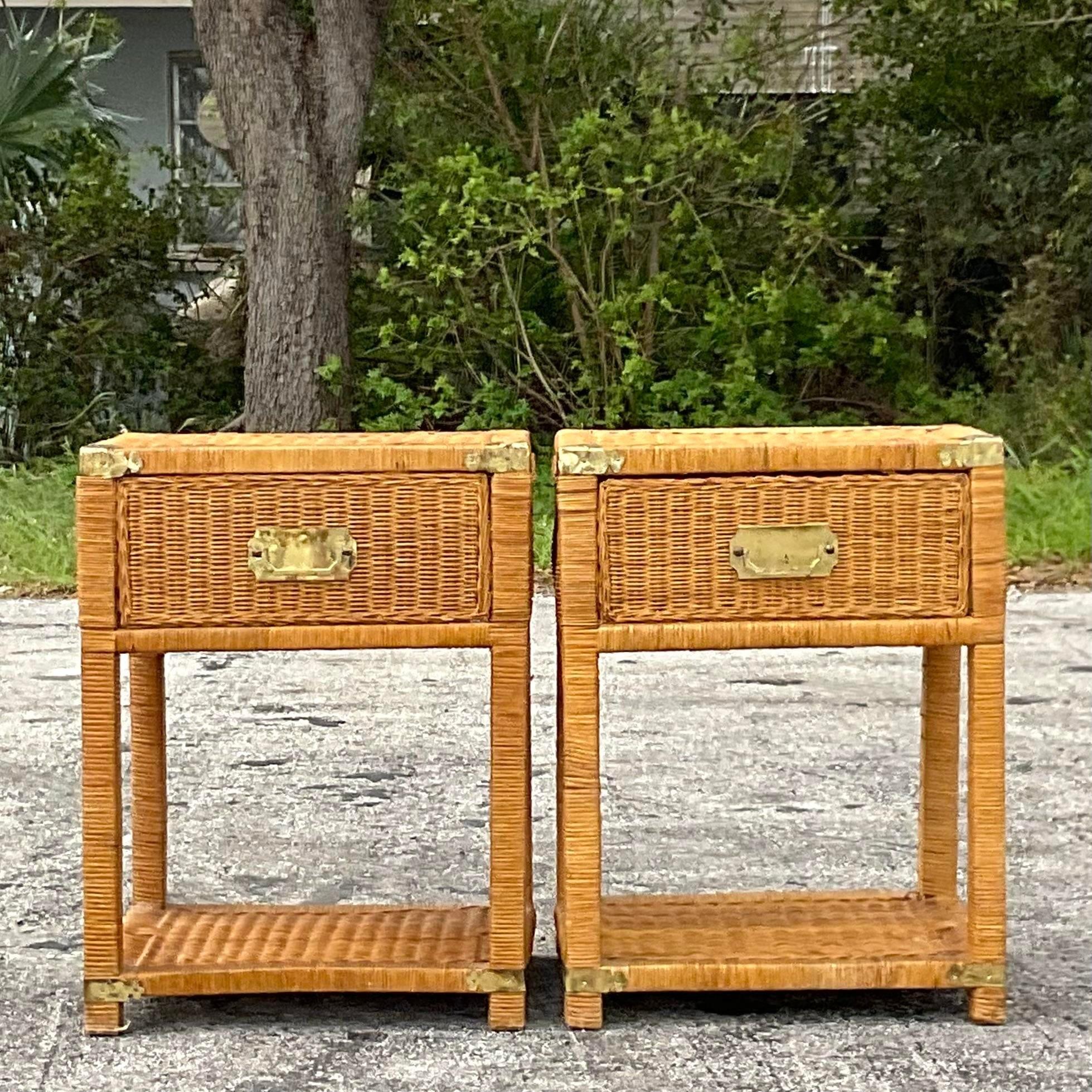 A fabulous pair of vintage Coastal nightstands. A chic woven rattan single drawer frame with brass campaign hardware. Lots of great open storage below. Acquired from a Palm Beach estate. 