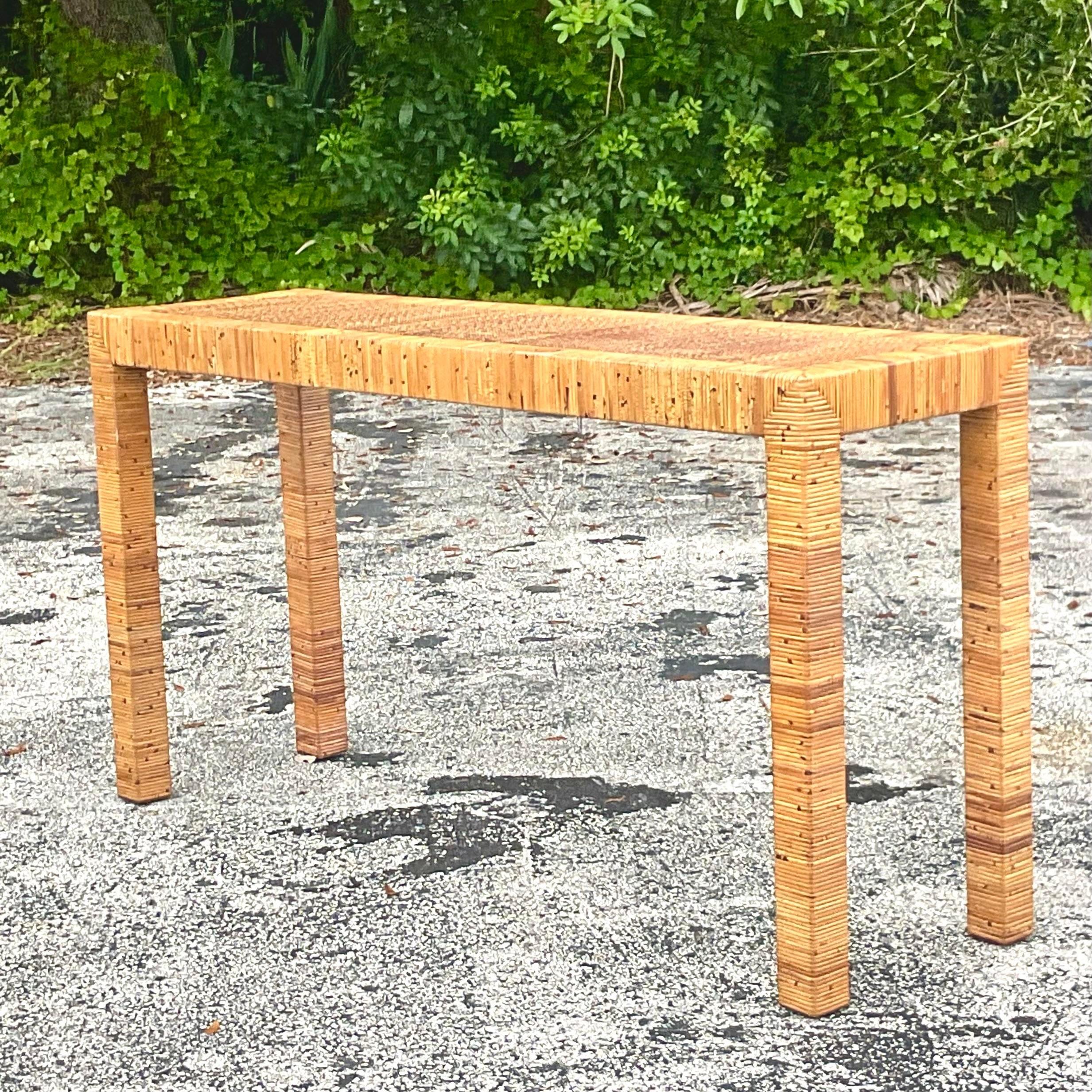 A fabulous vintage Coastal console table. A chic wrapped rattan in a classic parsons shape. Inset woven rattan top panel. Acquired from a Palm Beach estate.