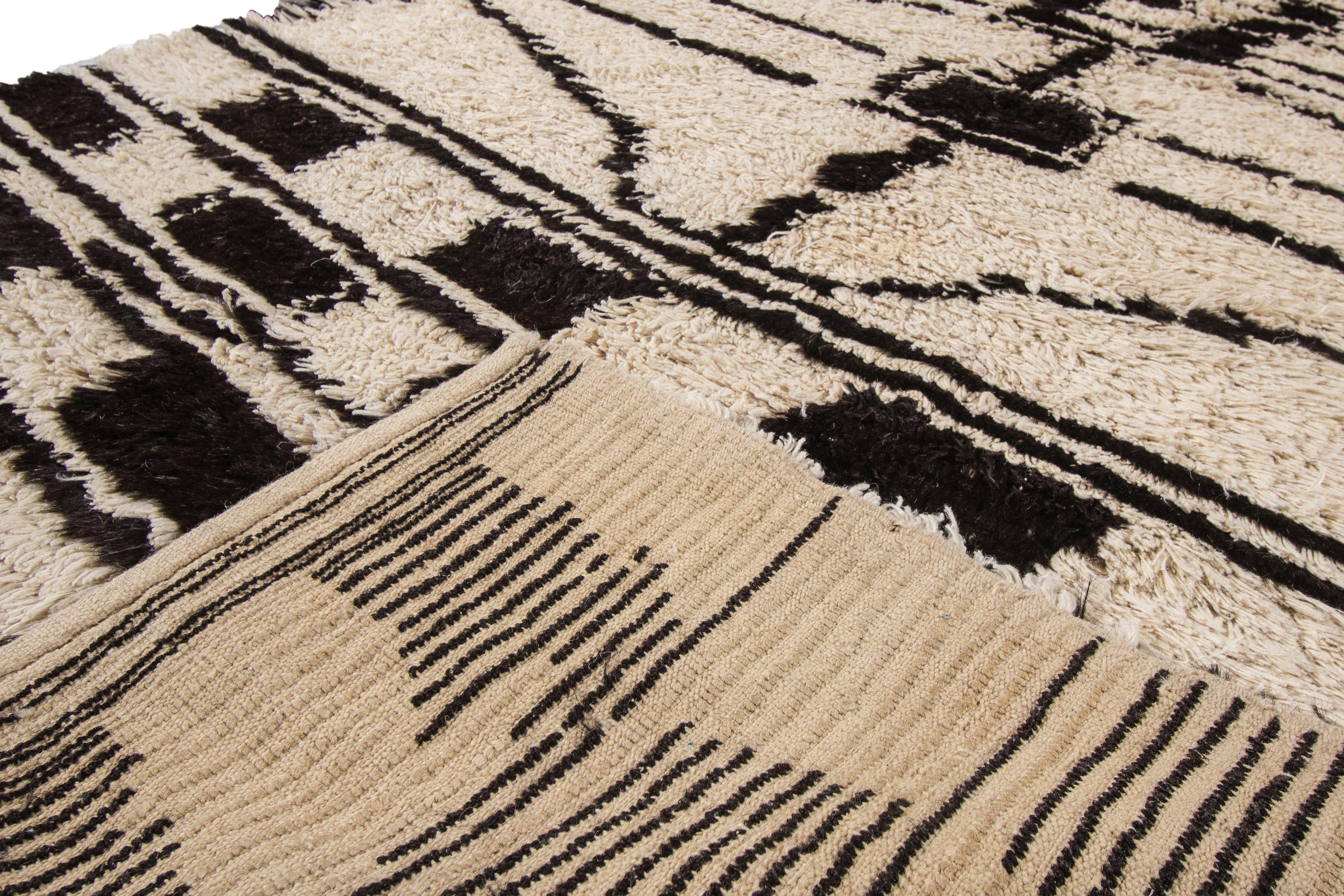 Beautiful vintage hand knotted Moroccan wool rug with an ivory field on artistic design. Accents of black and beige throughout the piece. 

This rug measures: 5'2
