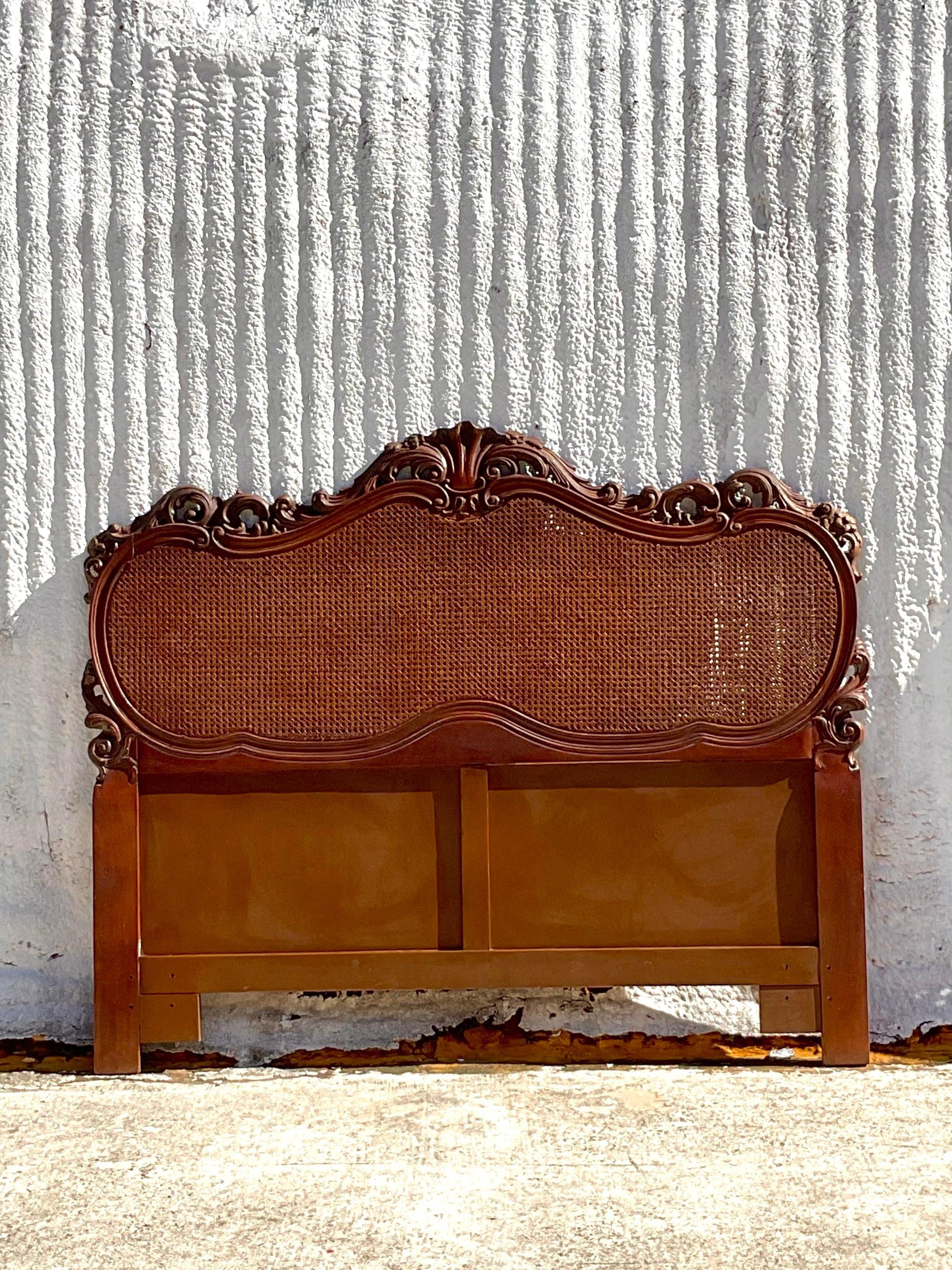 A gorgeous vintage headboard in a French style with cane on both the front and the back. We have a matching pair. The intricate wood carvings are delicate and gorgeous. Acquired at a Palm Beach estate.