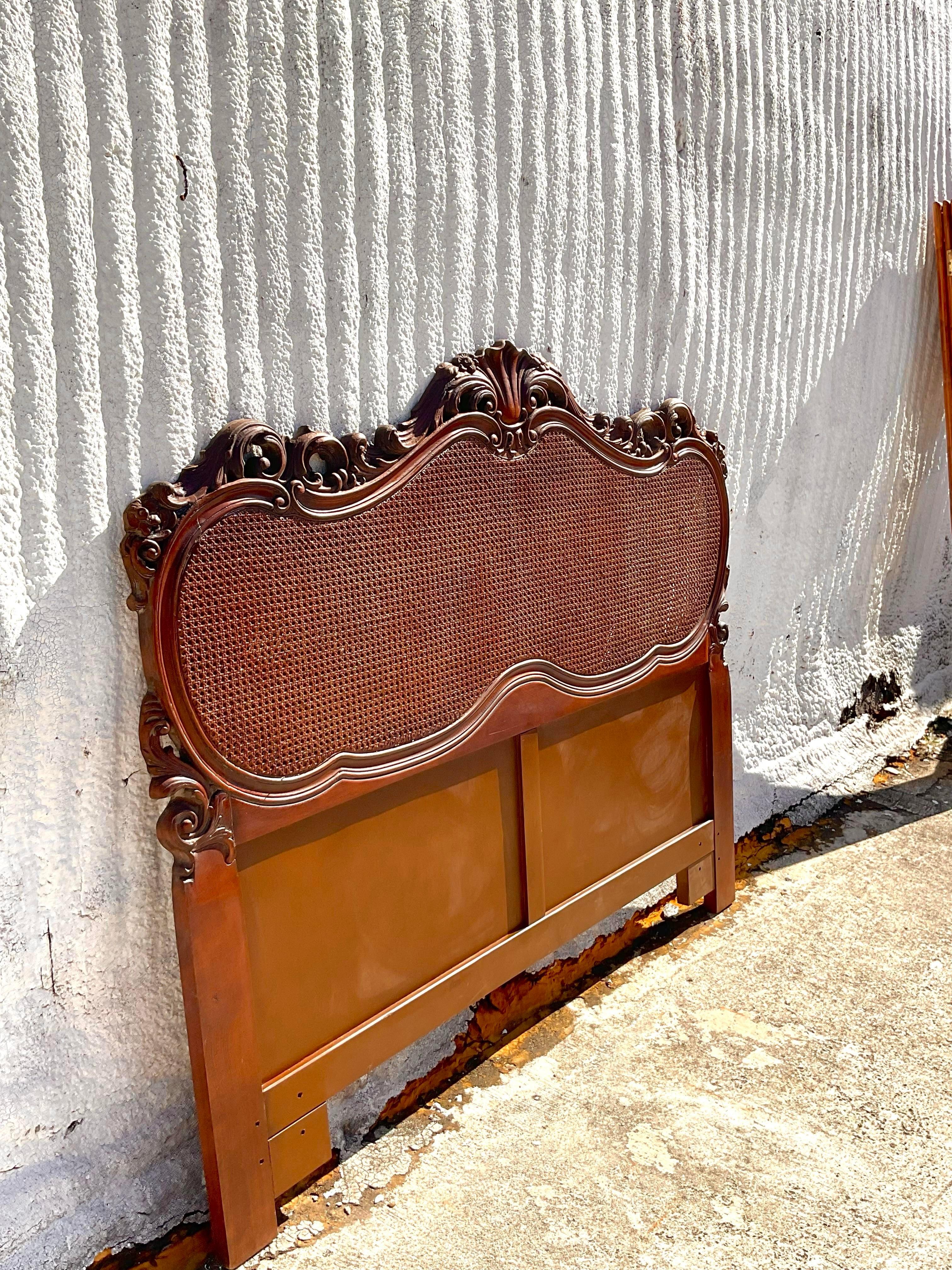 A gorgeous vintage headboard in a French style with cane on both the front and the back. We have a matching pair. The intricate wood carvings are delicate and gorgeous. Acquired at a Palm Beach estate.
