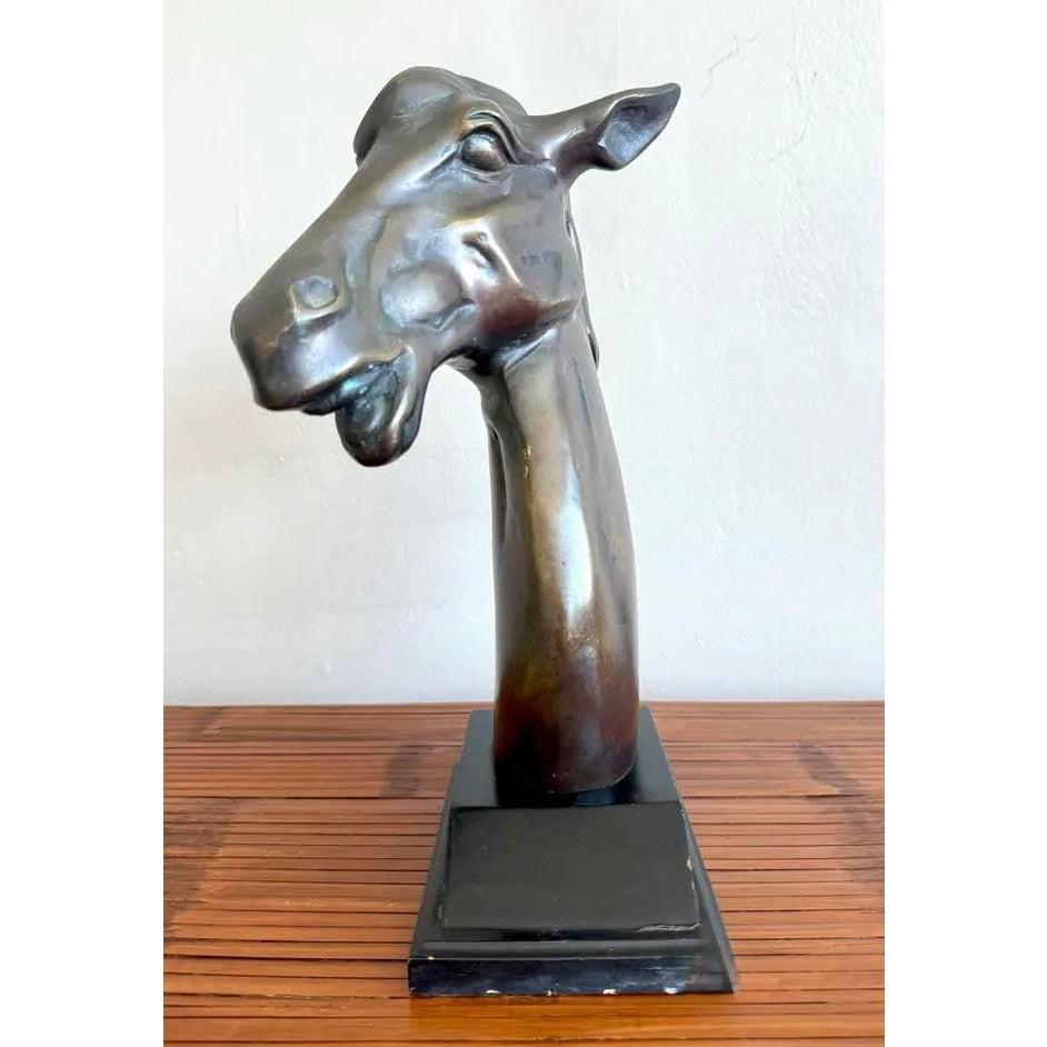 Questa scultura in bronzo con testa di cavallo presenta una forma forte e allungata con dettagli espressivi nella criniera e nel muso. La finitura è invecchiata con accenni di patina, che conferisce un senso di atemporalità e carattere. Poggiata su