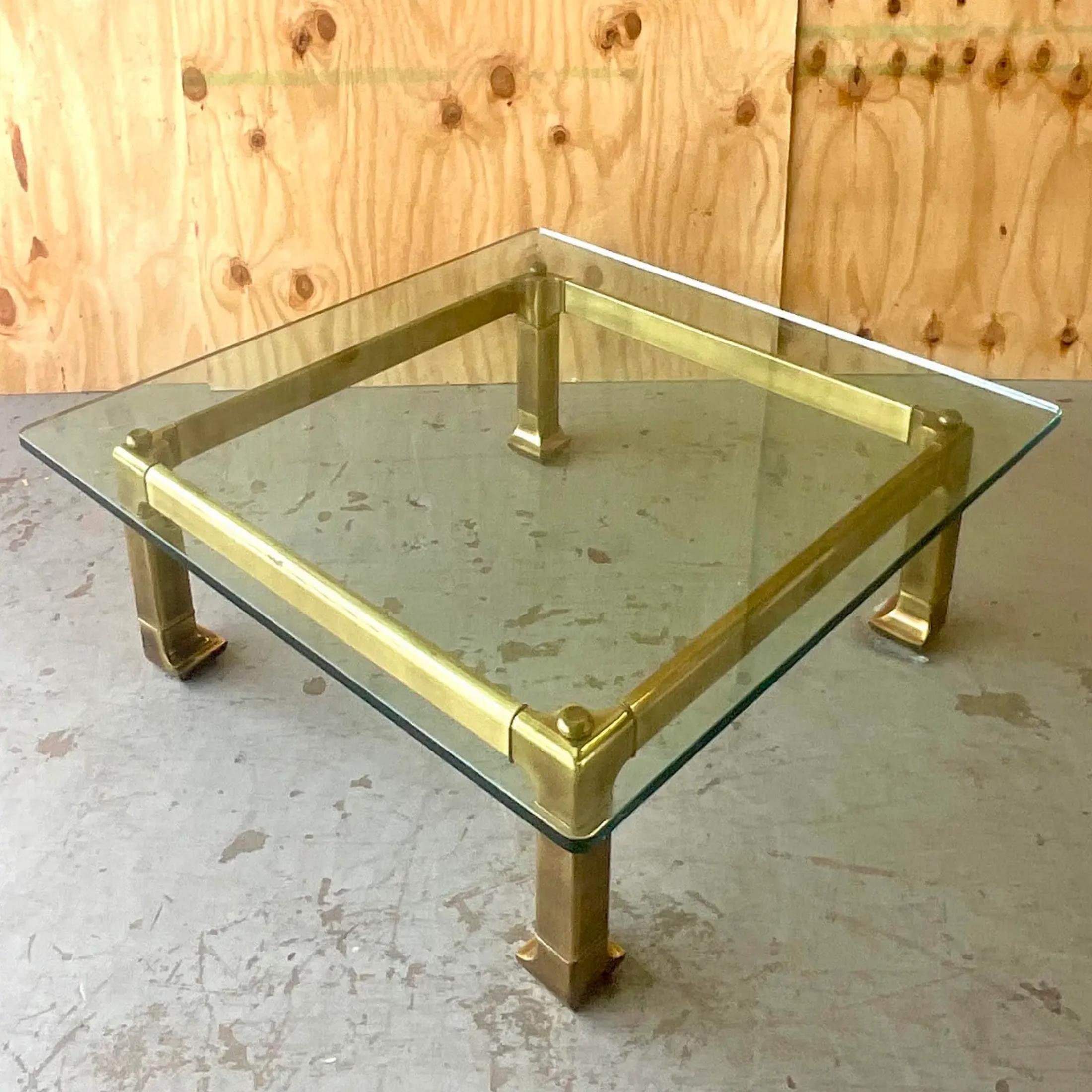 A stunning vintage Regency coffee table. A chic brass frame with thick glass top done in the manner of Mastercraft. Acquired from a Palm Beach estate.