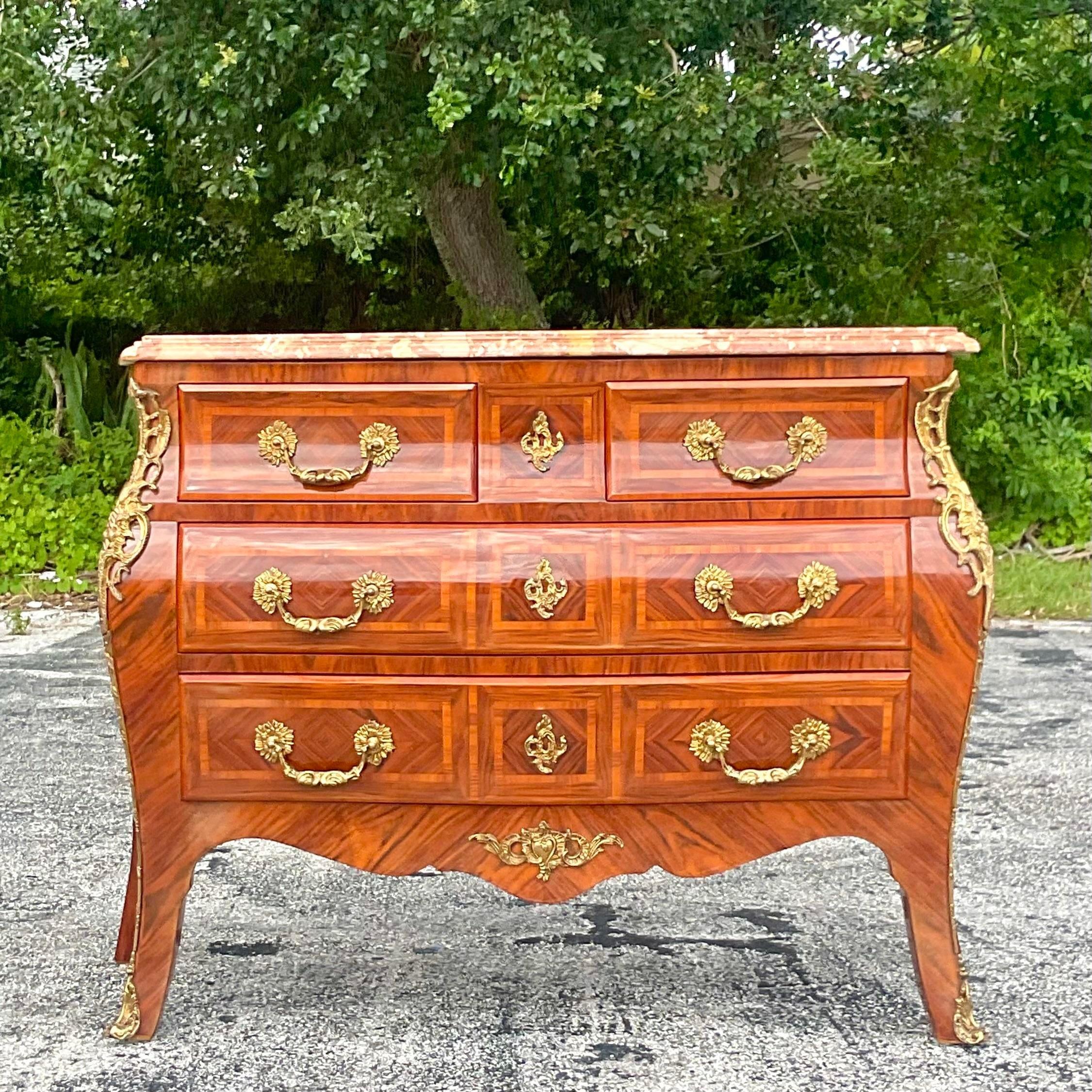 A fabulous vintage Regency Bombe chest. Beautiful Marquetry detail with gorgeous brass Ormolu details. Stunning stone top with a beveled bull nose edge. Acquired from a Palm Beach estate.