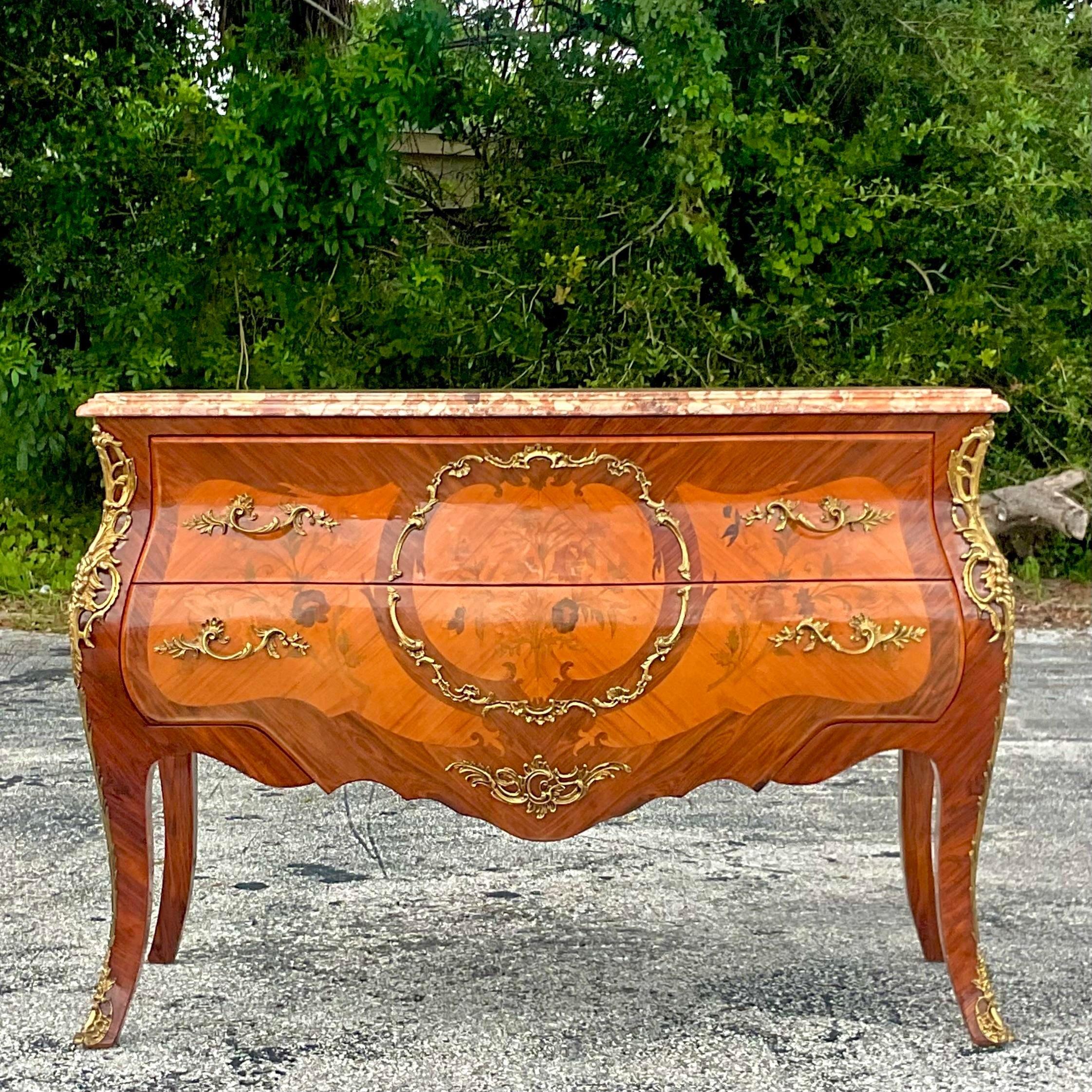 A fabulous vintage Regency chest of drawers. Beautiful floral marquetry detail with brass Ormolu detail. Fabulous stone top with beveled edge top. Acquired from a Palm Beach estate