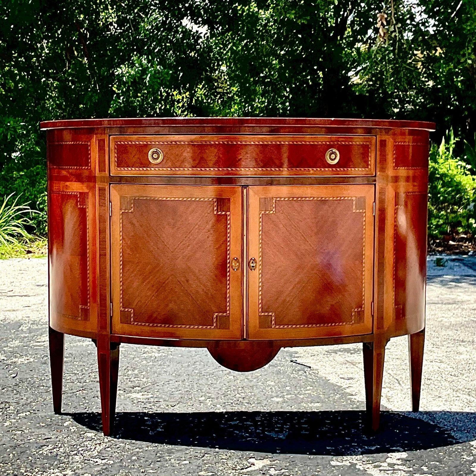 A fabulous vintage Regency console cabinet. A chic Demilune shape with gorgeous marquetry detail. Beautiful flame mahogany with brass hardware. Acquired from a Palm Beach estate.