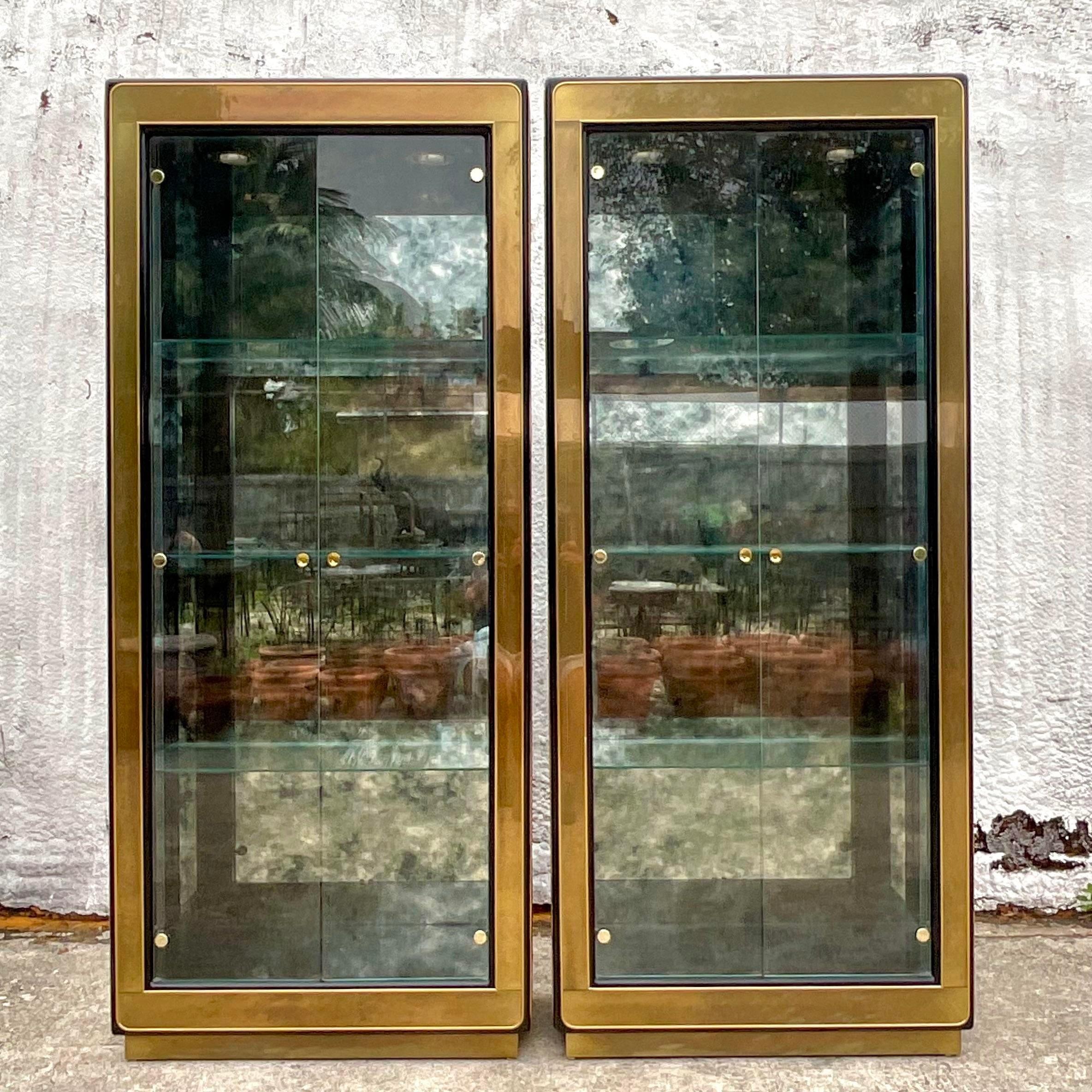 A striking pair of vintage Regency etagere. Made by the iconic Mastercraft group and tagged on the back. Burnished brass frame. Open glass walls and shelves and smoked mirror back panel. Acquired from a Palm Beach estate.