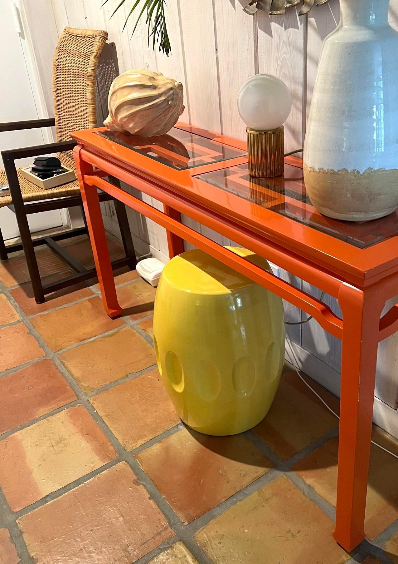 A stunning vintage Regency console table. A chic brilliant orange lacquer Finnish on a classic fretwork design. Inset glass top. Acquired from a Palm Beach estate.
